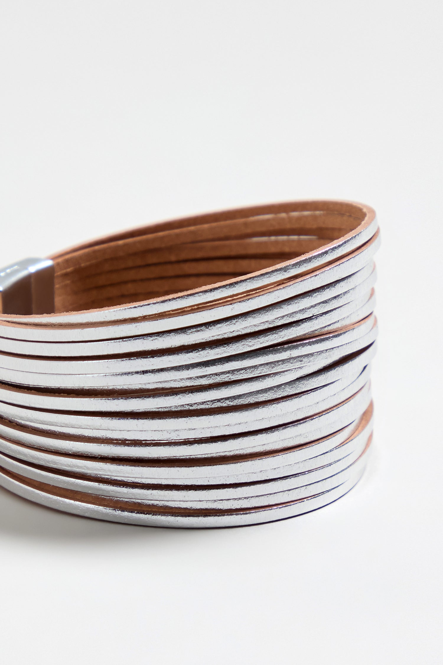 A close-up of the Vegan Leather Metallic Bracelet, a lightweight, multi-strand, metallic silver accessory, coiled on a plain white background.