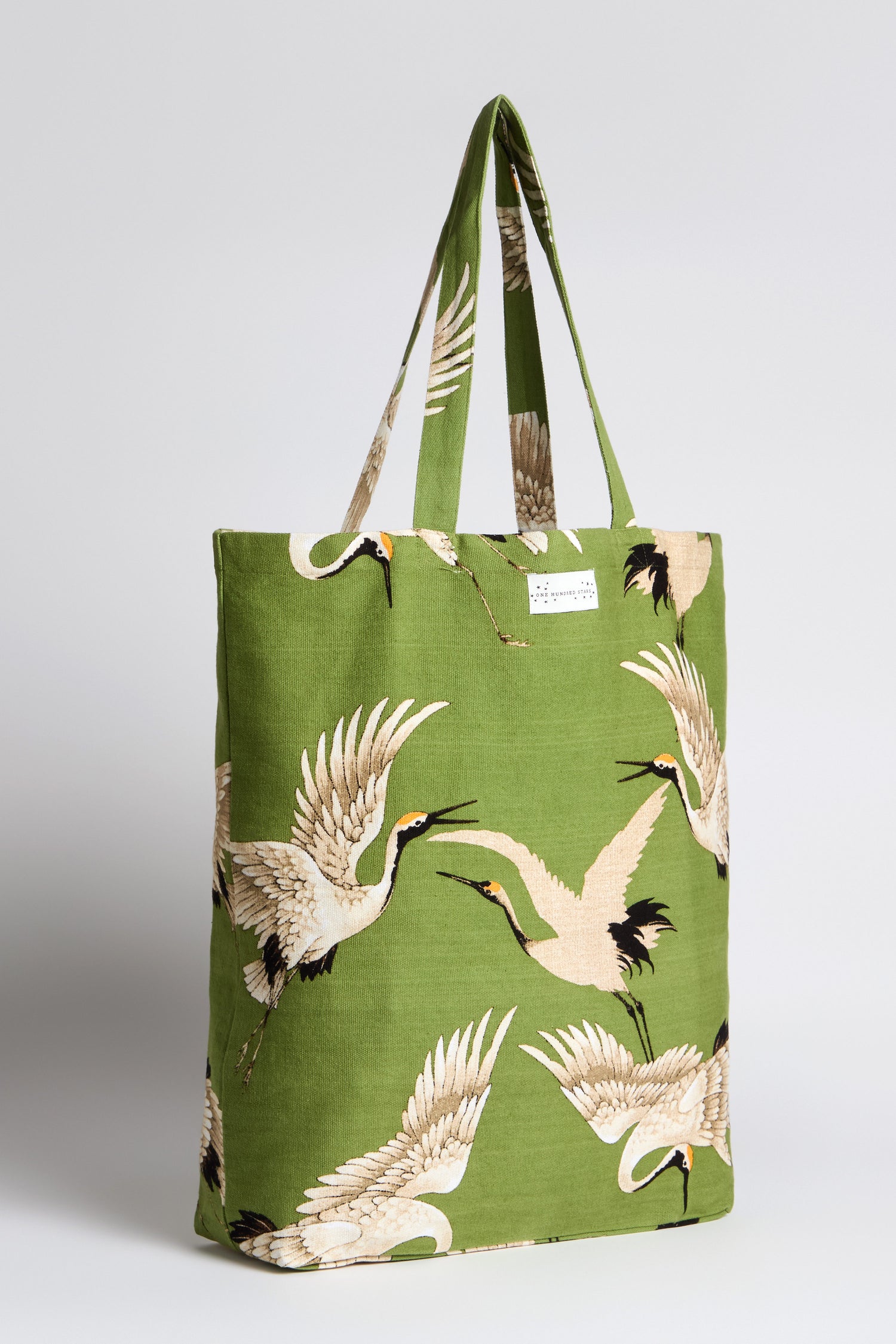 The Stork Print Canvas Bag brings Art Deco fashion to life with its green shade and crane bird design. Featuring two handles and a small top-center label, this sustainable cotton tote is perfect for stylishly carrying essentials.