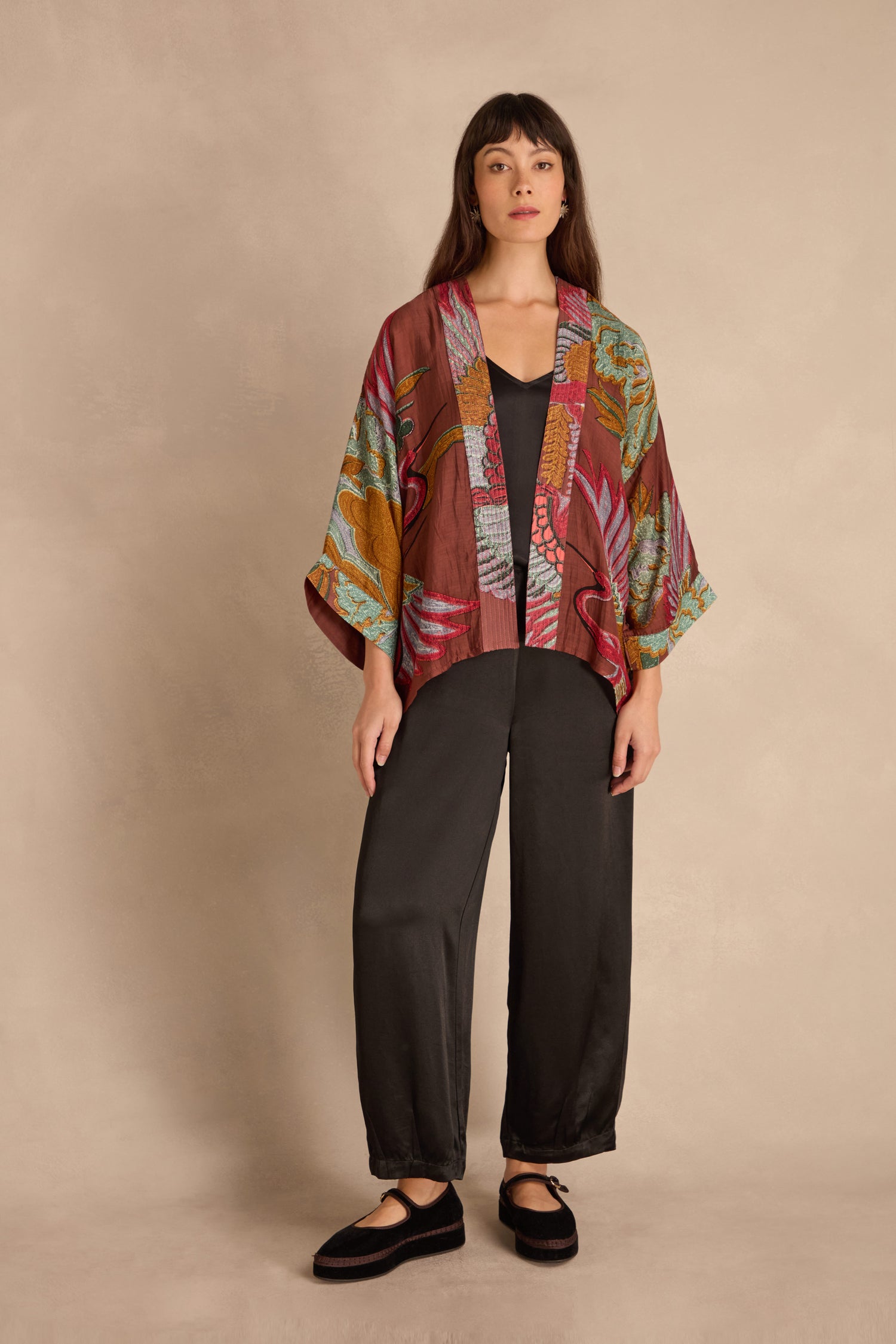 Woman stands facing forward, wearing the Crane Kimono over a black top and pants with black shoes, against a neutral background.