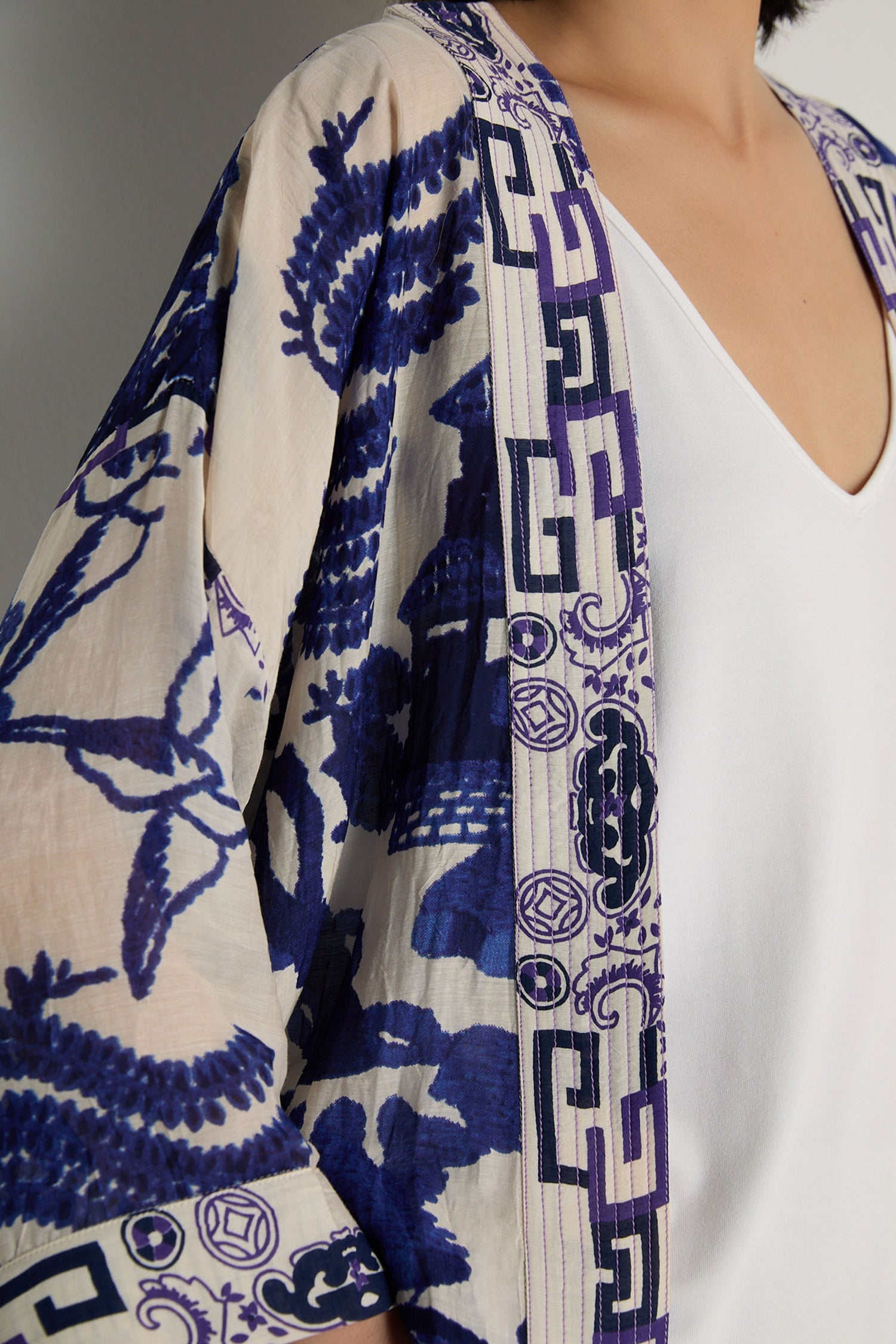 A person wears a white V-neck top and the Willow Print Kimono, which features cream fabric with blue and purple abstract and geometric patterns in a relaxed fit.