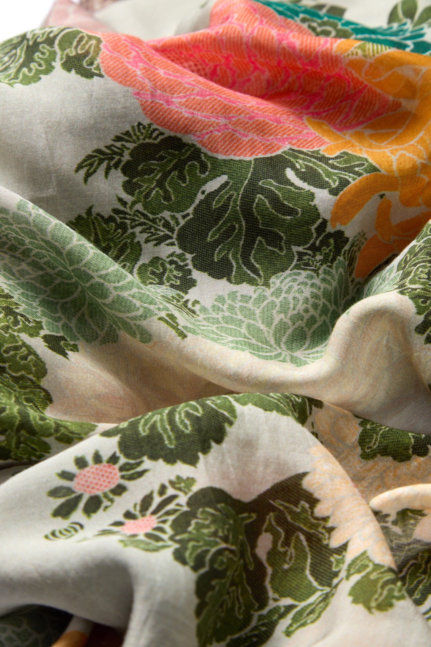 A close-up of the Jacquard Scarf’s crumpled, vintage-style floral fabric with green leaves and pink, orange, and yellow flowers.
