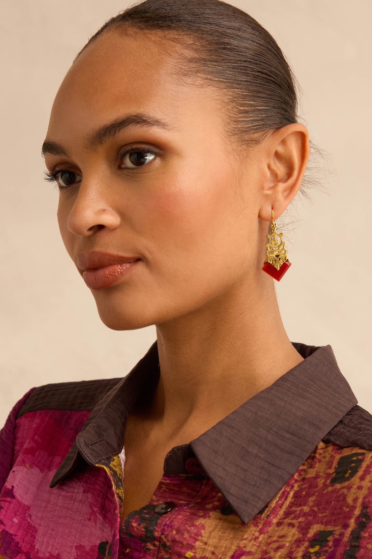 A model wearing Gold-Plated Carnelian Drop Earrings, featuring geometric carnelian stones in gold.