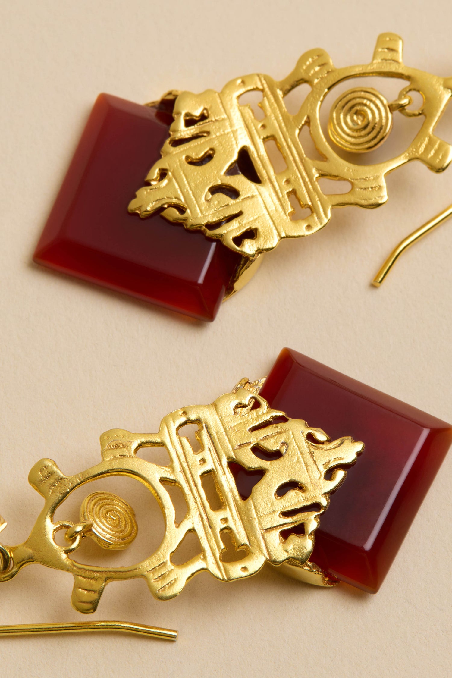 Close-up of Gold-Plated Carnelian Drop Earrings featuring geometric gold designs and square carnelian stones on a neutral background.