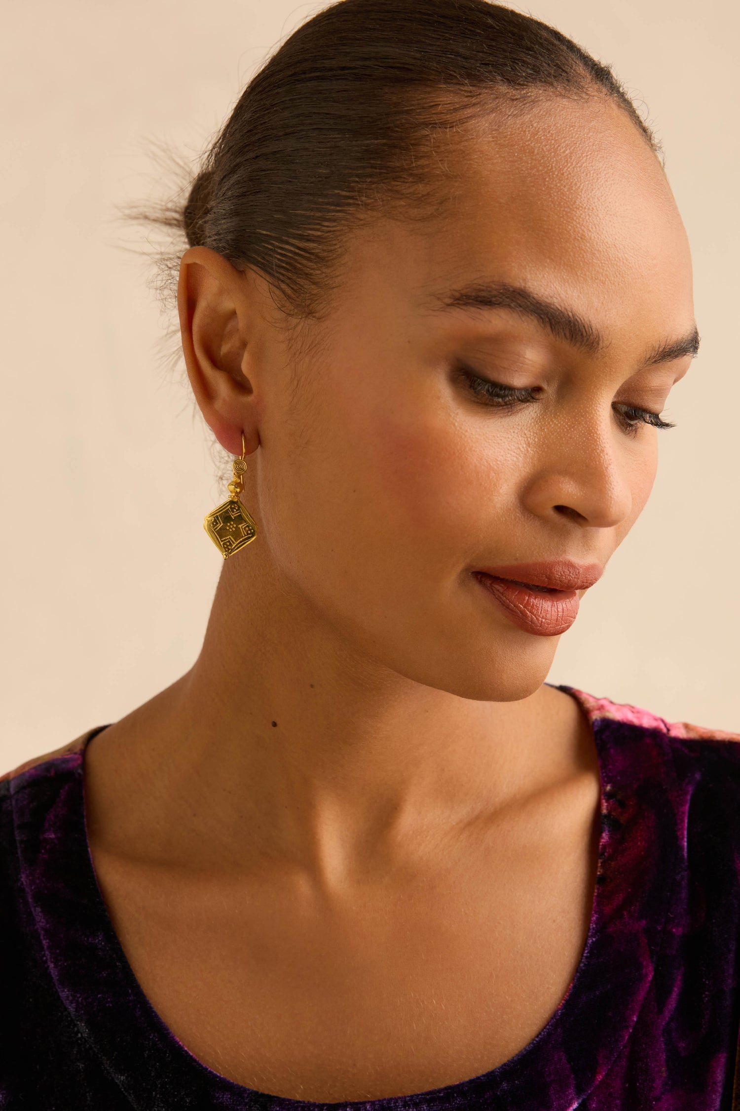 A person wearing Gold-Plated Square Drop Earrings featuring incised surface detailing in a geometric pattern.