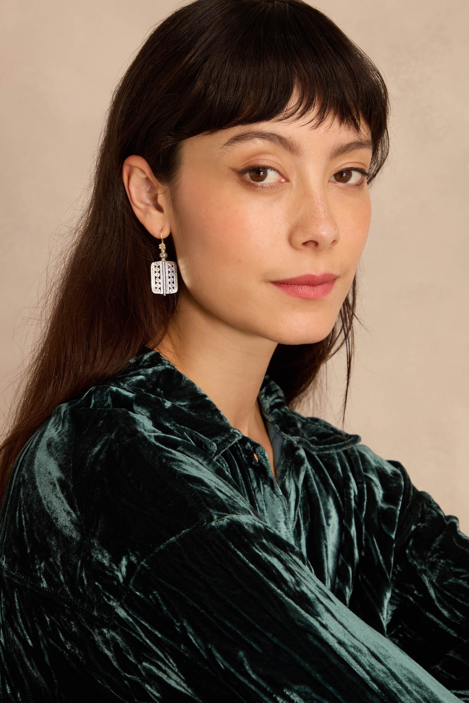 Woman with long dark hair and bangs wears a green velvet top and Filigree Drop Earrings, looking at the camera against a neutral background.