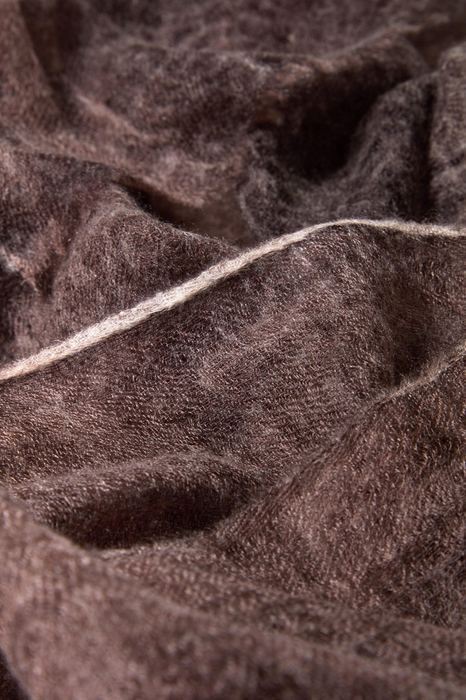 Close-up of the Soft Espresso Cashmere Scarf’s plush, brown fabric with a visible diagonal seam, capturing the luxurious texture and rich color of this elegant accessory.