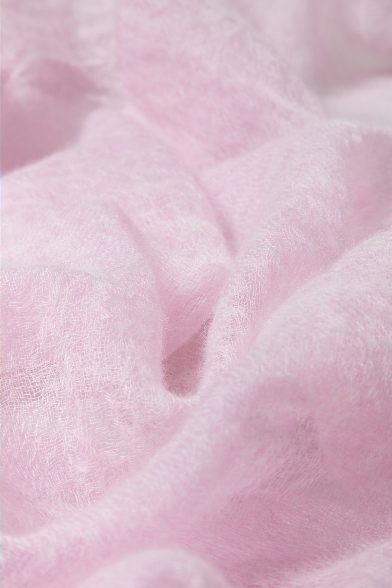 Close-up of the Soft Blush Cashmere Scarf shows soft, light pink fabric with a slightly sheer, textured look and delicate folds—ideal for a lightweight accessory or elegant blush scarf.