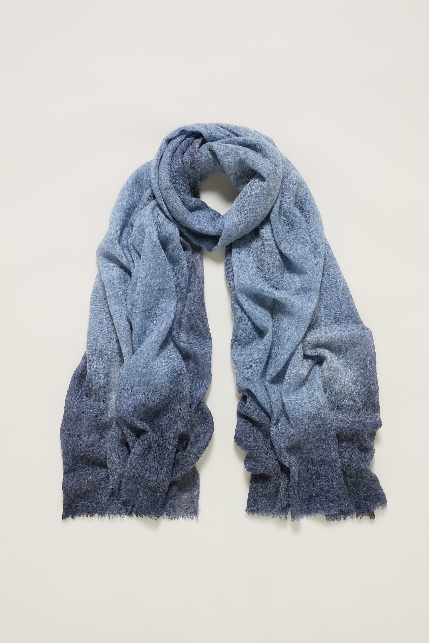 The Night Sky Gradient Cashmere Scarf, featuring a soft, textured fabric and lightweight feel, is displayed flat on a light background to highlight its delicate blue gradient design.