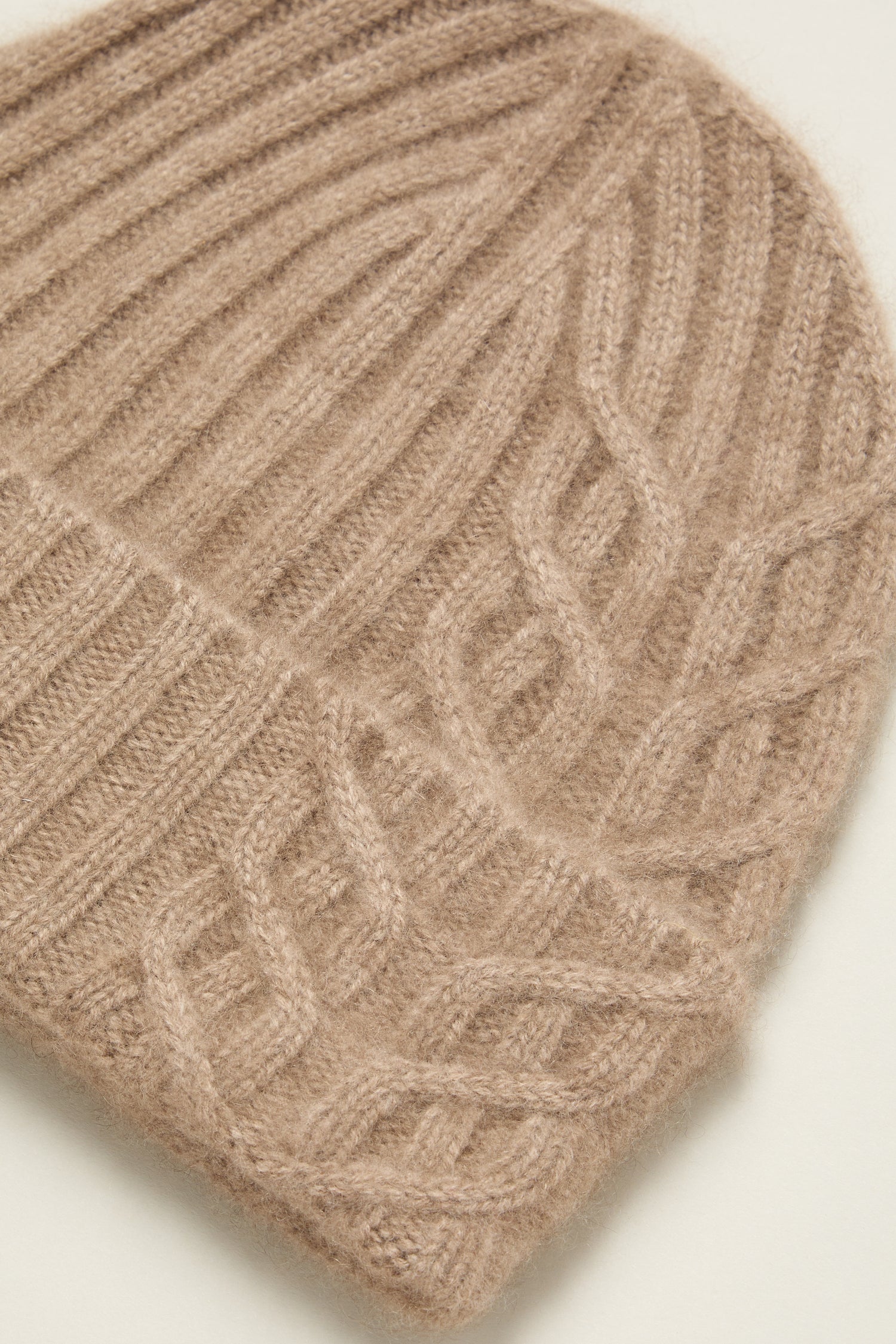 Close-up of the Warm Sands Ribbed Cashmere Hat in beige, showcasing elegant cable knit patterns—a cozy winter accessory.