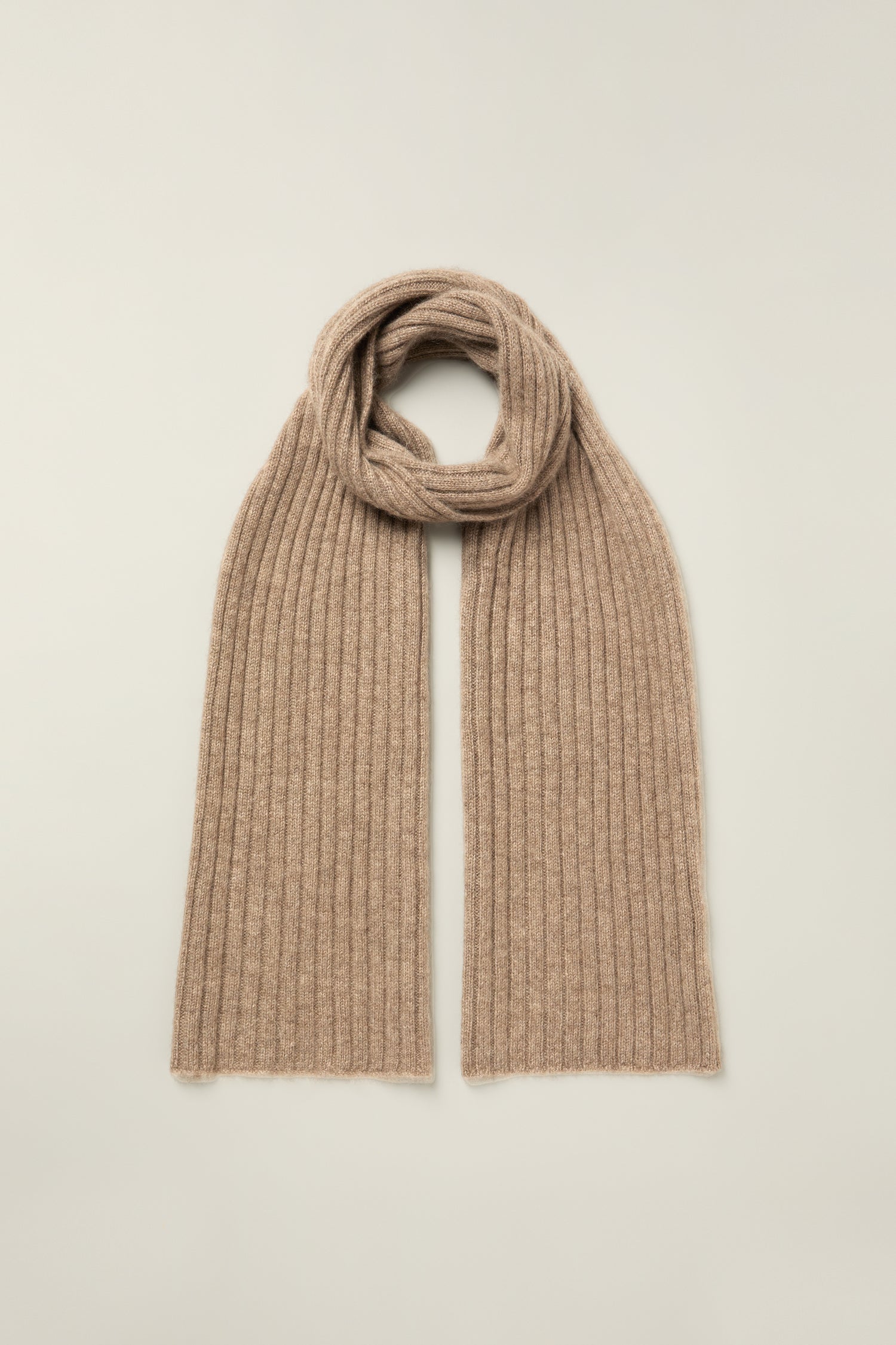 The Warm Sands Ribbed Cashmere Scarf is laid flat on a light background, its ends spread out and middle loosely looped—a cozy essential to elevate your winter wardrobe.