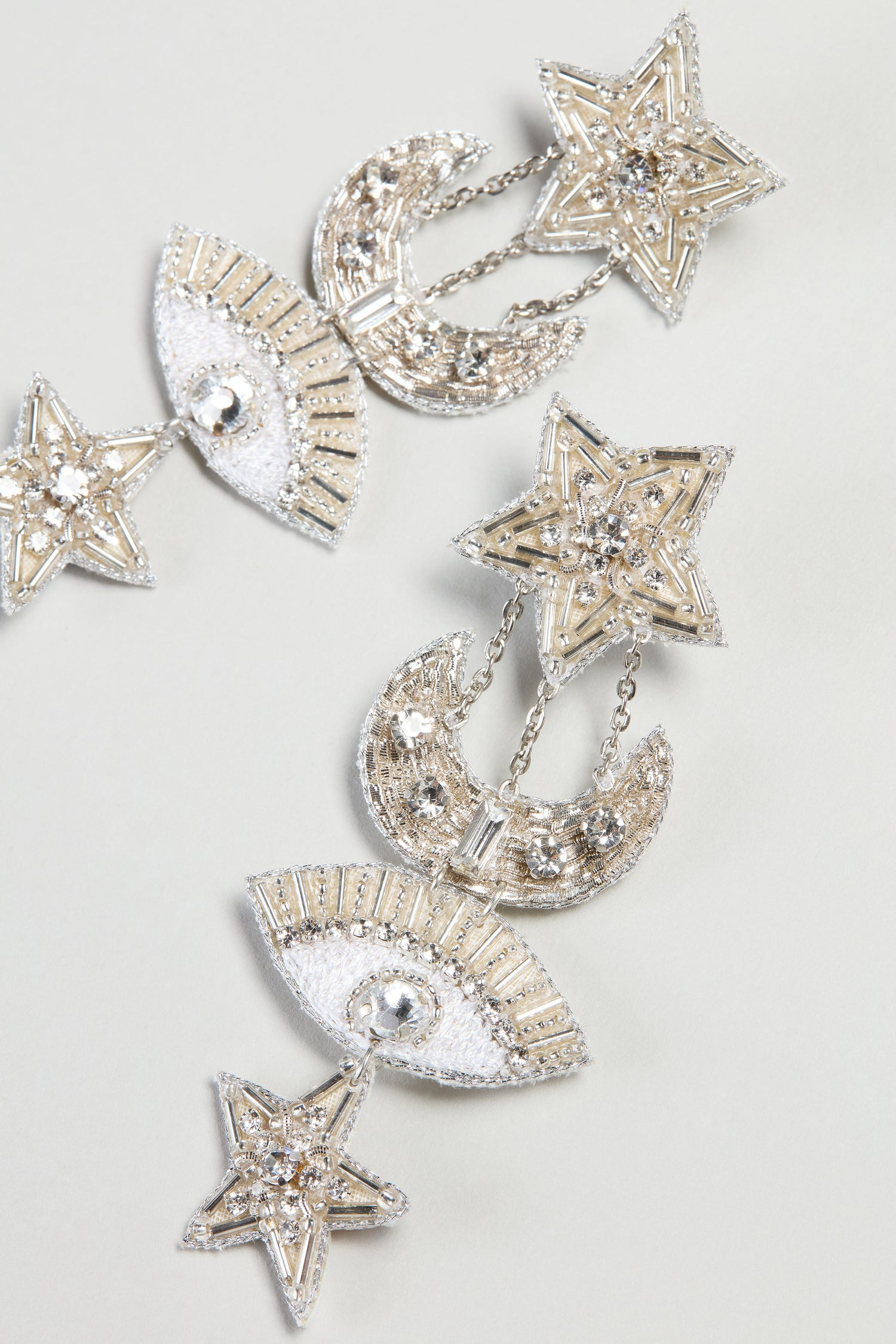 Hand Beaded Celestial Silver Earrings from Psquuare Fashion Jewellery feature dangling star, moon, and eye shapes with silver rhinestones and metallic accents, displayed on a light background.