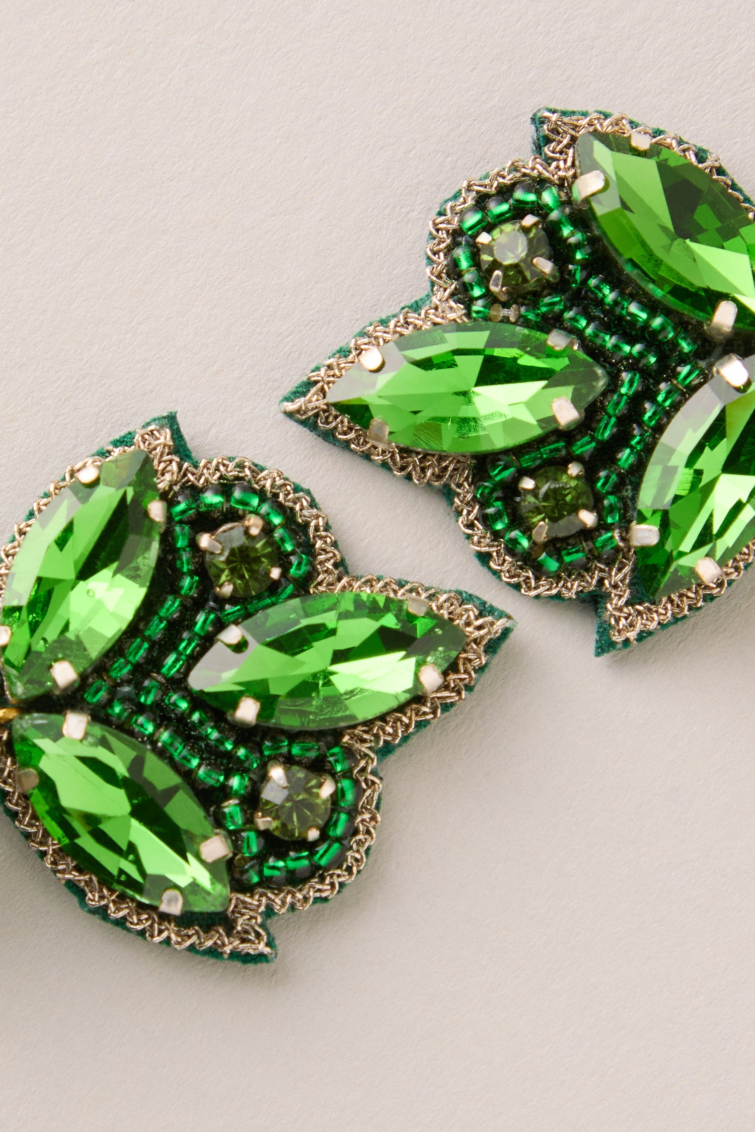Close-up of Hand Beaded Flower Earrings featuring green gemstones, small beads, and metallic trim in an intricate pattern—ideal for artisan jewelry lovers.
