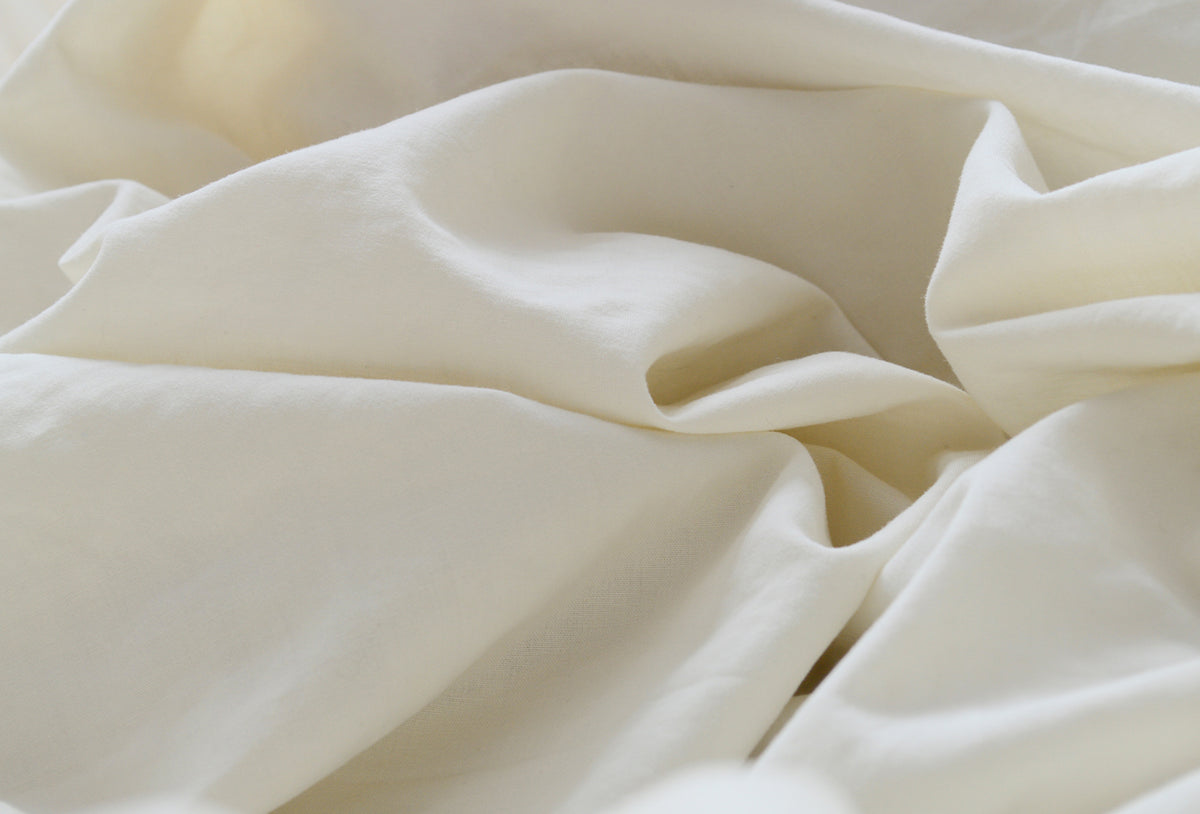 A image of crumpled beige polyester fabric with soft, flowing folds.