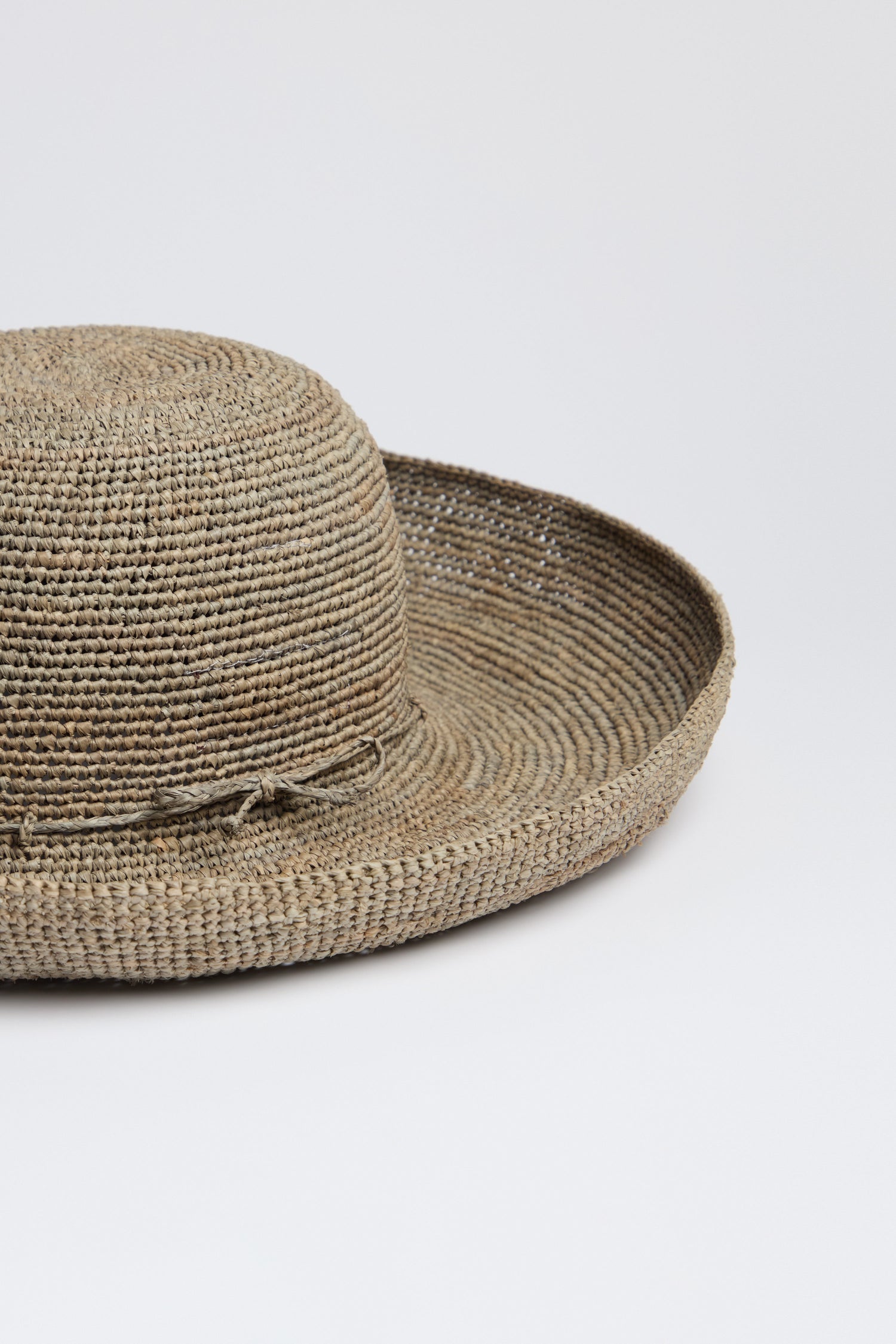 The Handwoven Wide Brim Raffia Hat features a wide brim and subtle ribbon detail for excellent sun protection, displayed on a plain white background.