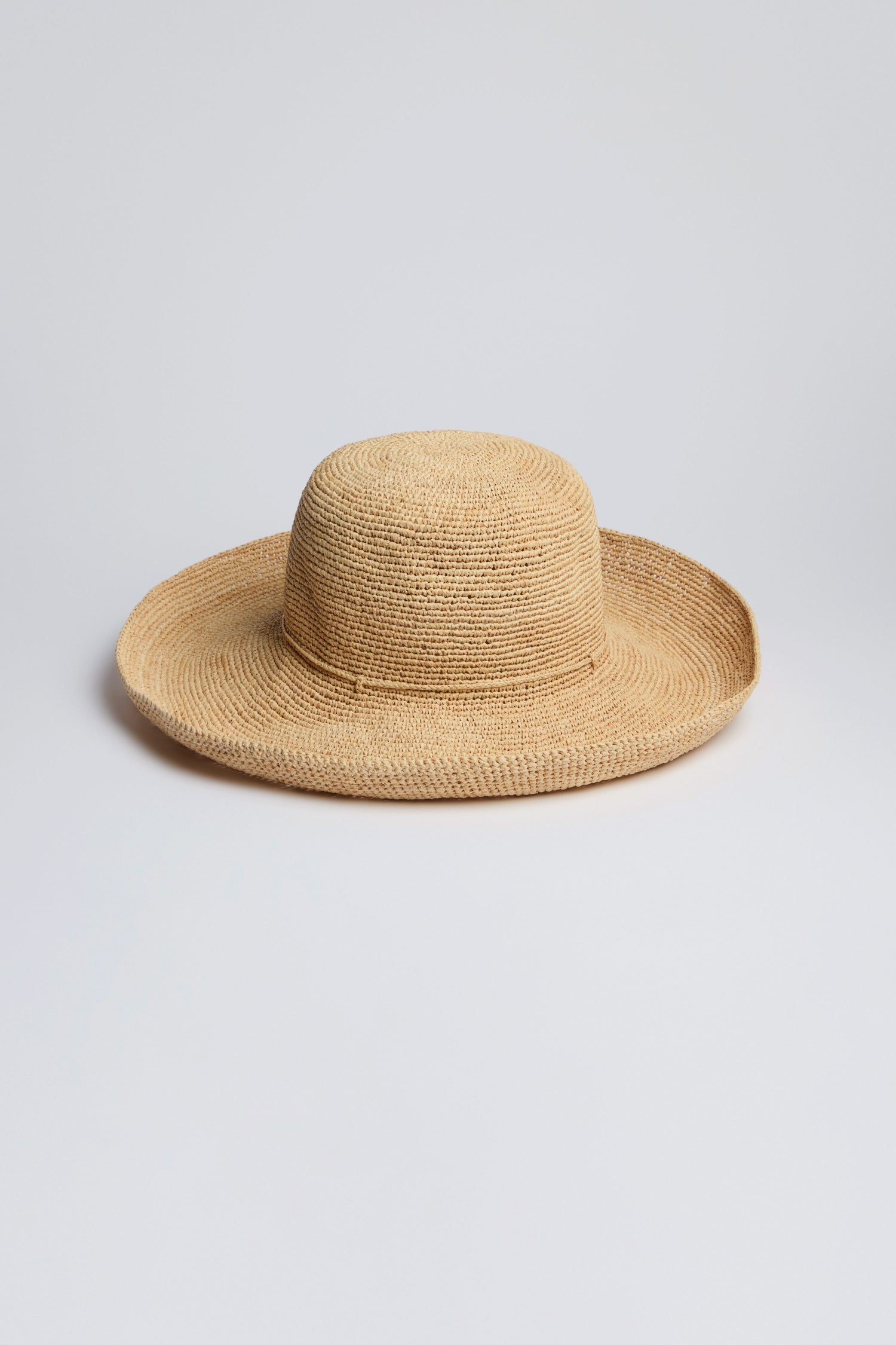 The Handwoven Wide Brim Raffia Hat sits elegantly on a plain white background, offering stylish sun protection.