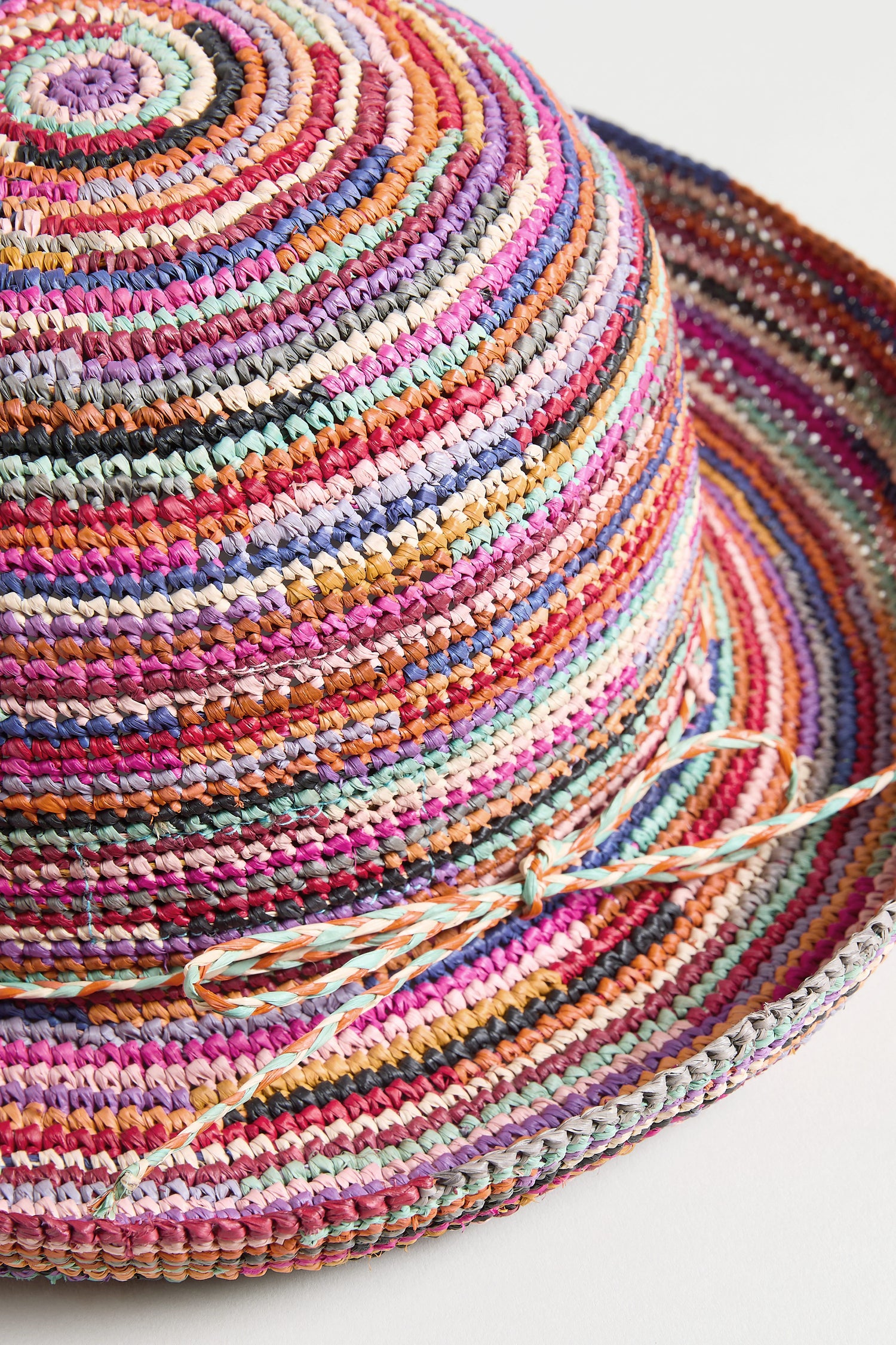 Close-up of the Handwoven Rainbow Raffia Hat, featuring vibrant stripes and a matching bow at the crown's base, skillfully crafted by artisans in Madagascar.