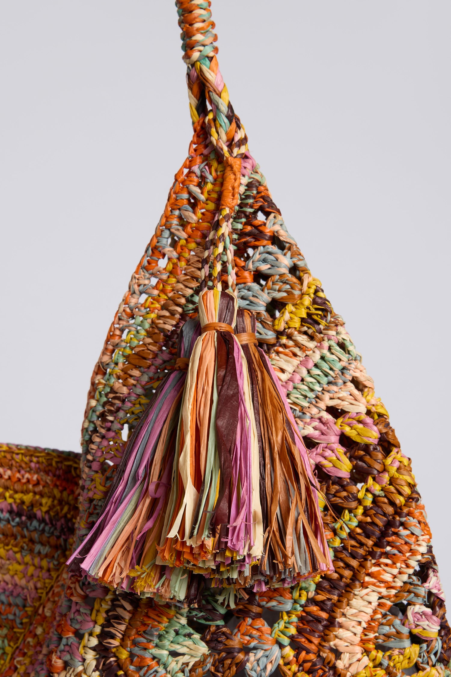 Close-up of the Handwoven Bohemian Raffia Bag, featuring a colorful woven body, braided handle, decorative fiber tassel, and a unique geometric patchwork design.