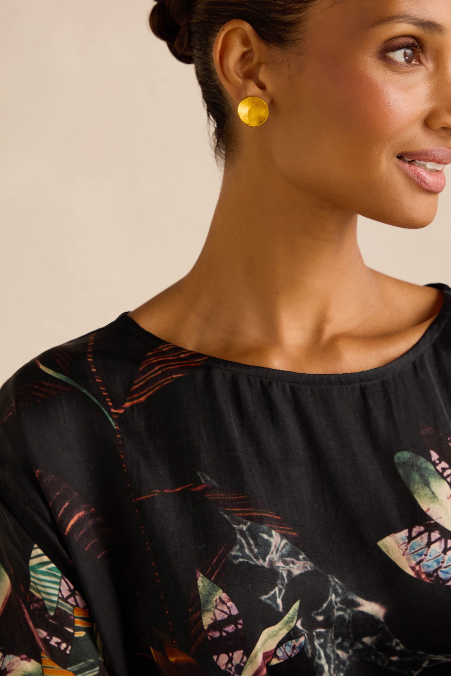 A woman wearing the Abstract Floral Boxy Top and gold circular earrings, facing partially to the right against a neutral background.
