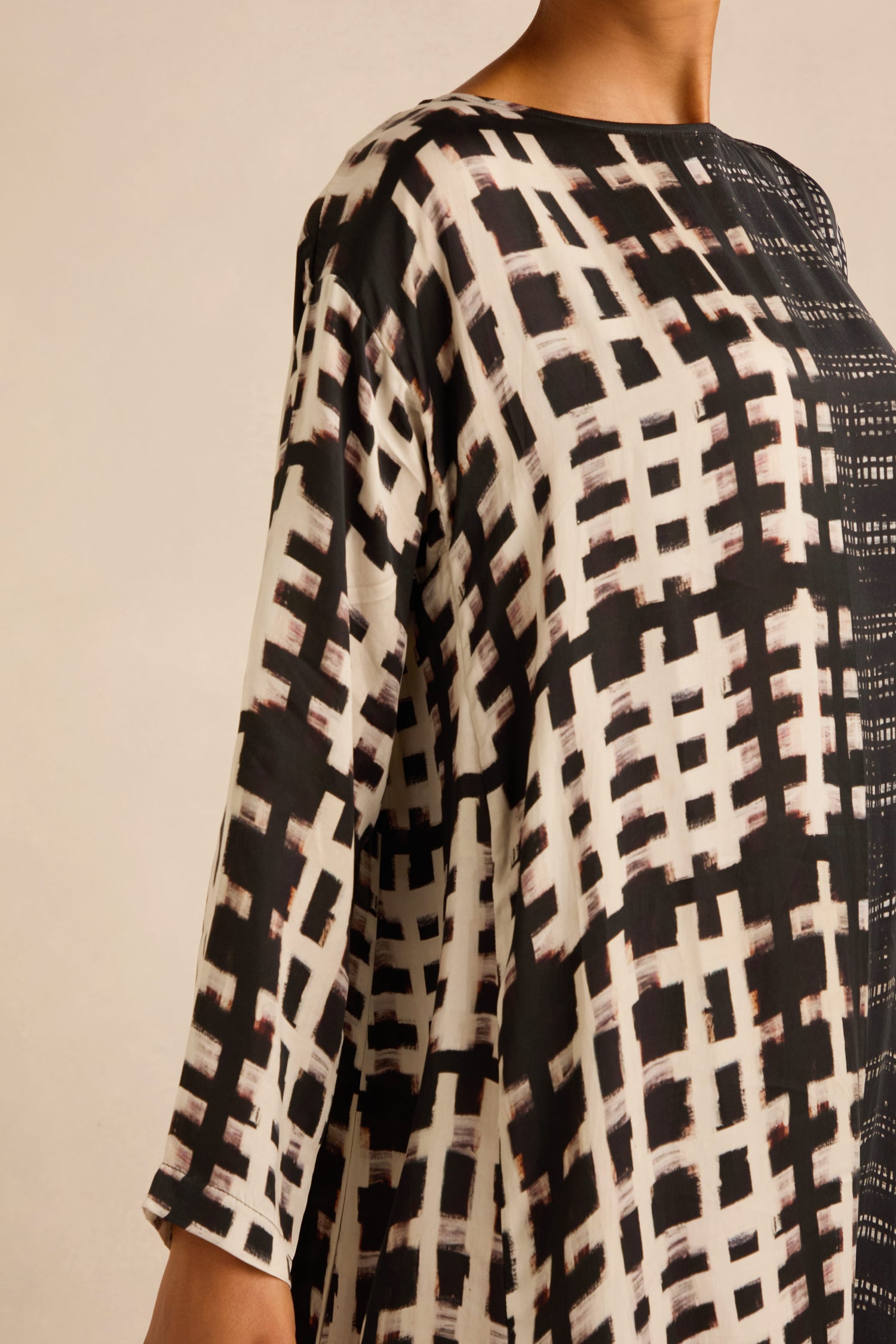 A person wearing the Check and Dash Easy Dress, a long-sleeved monochrome outfit featuring a black and white grid-like pattern, shown from the shoulders to the hip against a plain background.