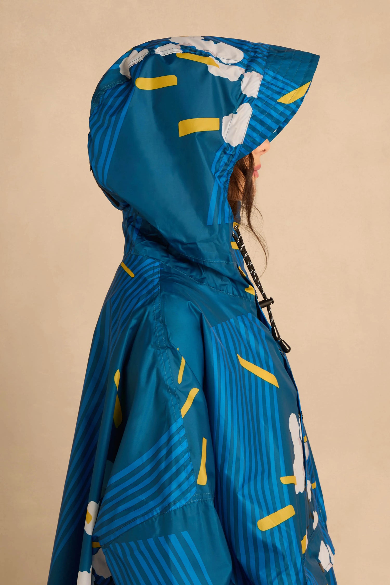 Person in profile wearing a Japanese Blue Blossom Poncho in blue with a yellow and white floral pattern and diagonal stripes.