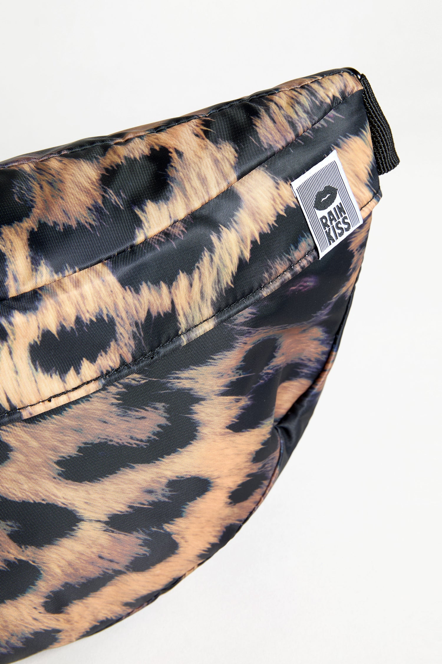 A close-up of the Dark Leopard Cross Body Bag, showing its dark leopard print and a "BIMBAYLOLA" brand tag attached to the zipper area.