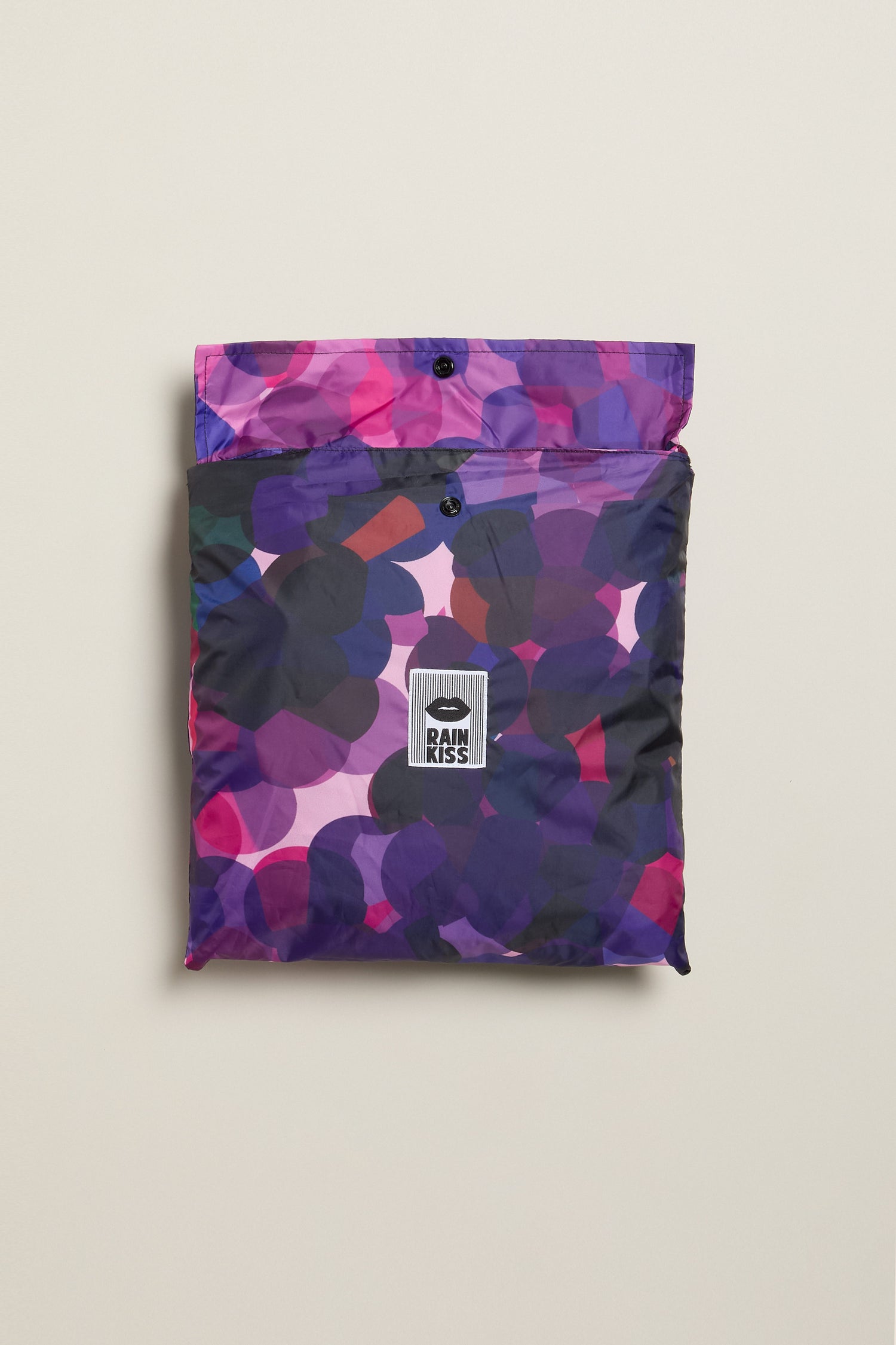City Lights Poncho featuring a purple, pink, and blue floral pattern made from recycled plastic with a "Rains" logo on the front.