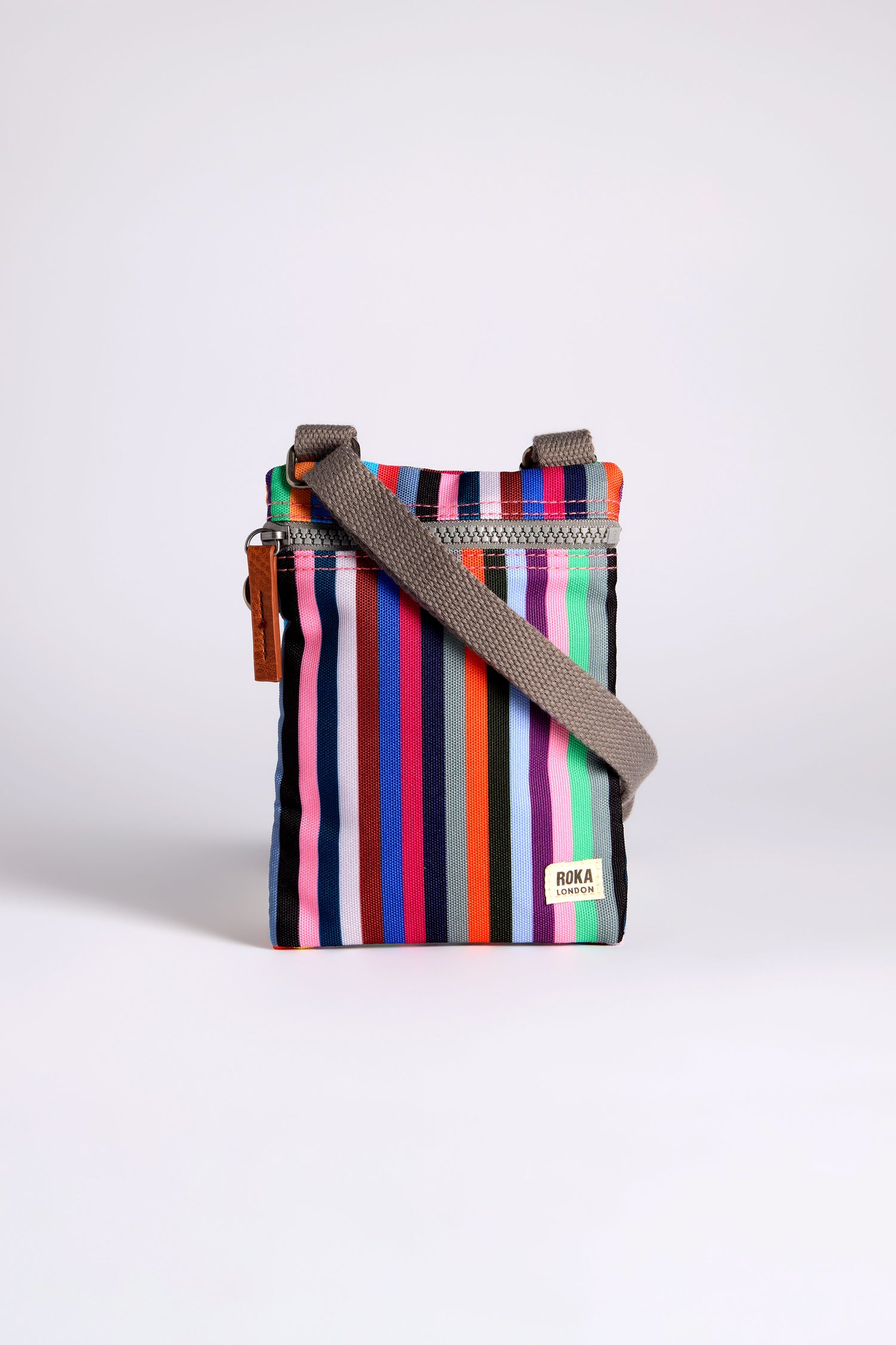 The Recycled Chelsea Crossbody Bag boasts colorful vertical stripes and a gray strap made from recycled materials. Its vibrant patterns pop against a plain background, making it stylish and weather-resistant for daily adventures.