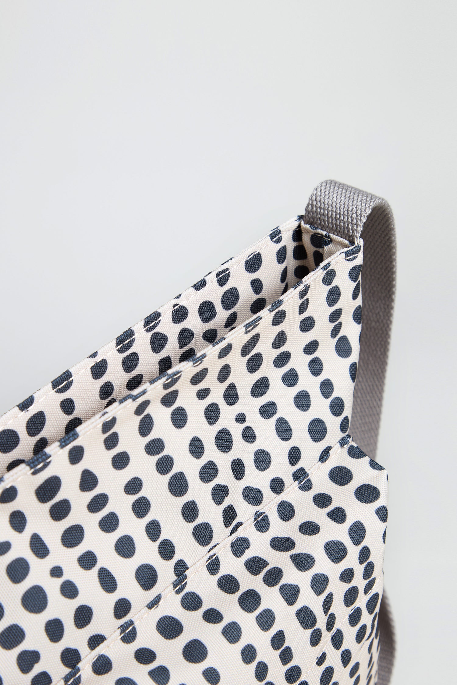 Close-up of the Recycled Canvas Kennington Dotty Bag, featuring a black dot pattern on a light background and a gray strap.