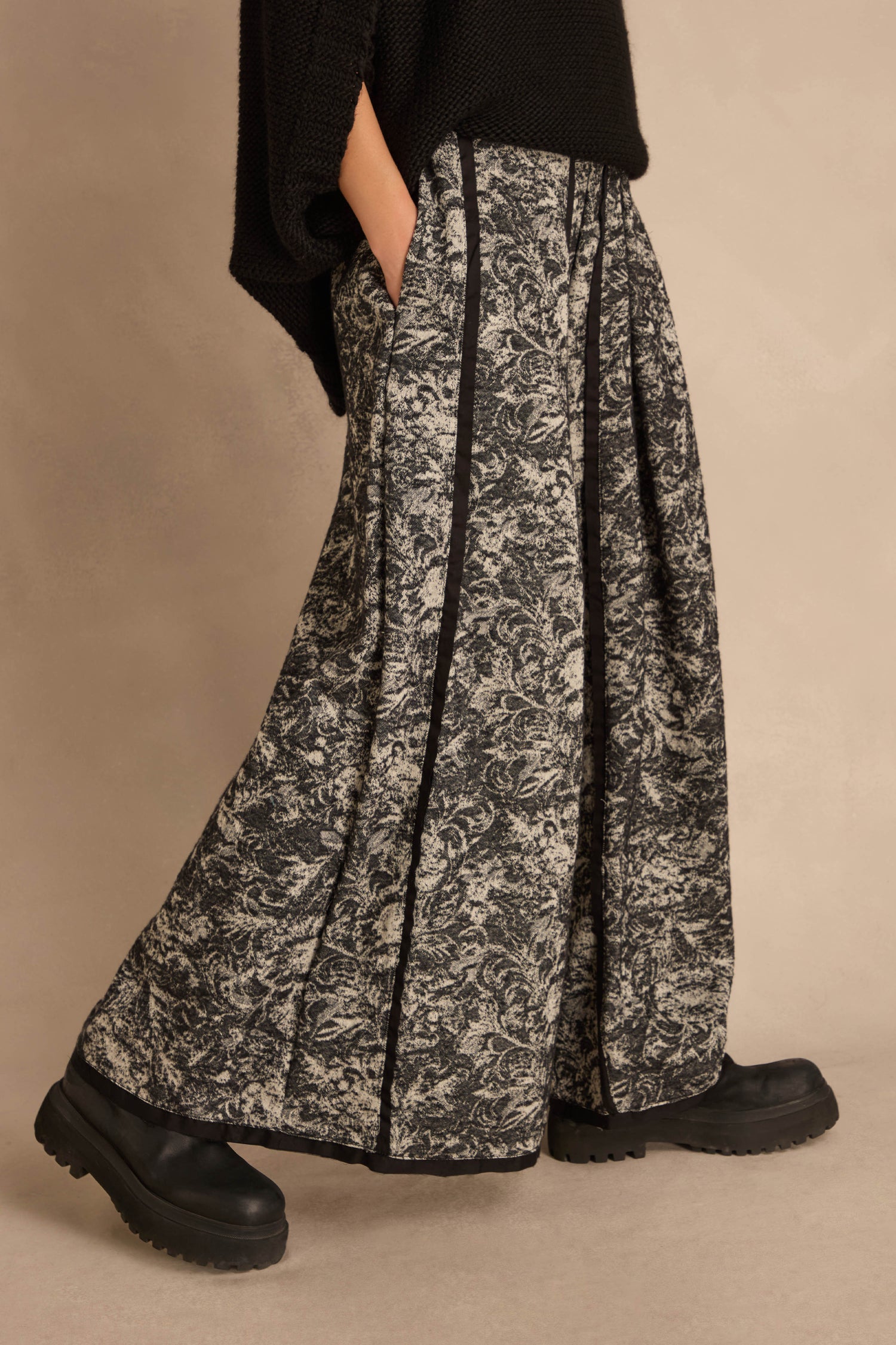 Frayed Hem Wide Leg Trousers in a cotton-rich woven fabric with a black and white floral pattern, vertical black piping, and a frayed hem, worn with black platform boots.