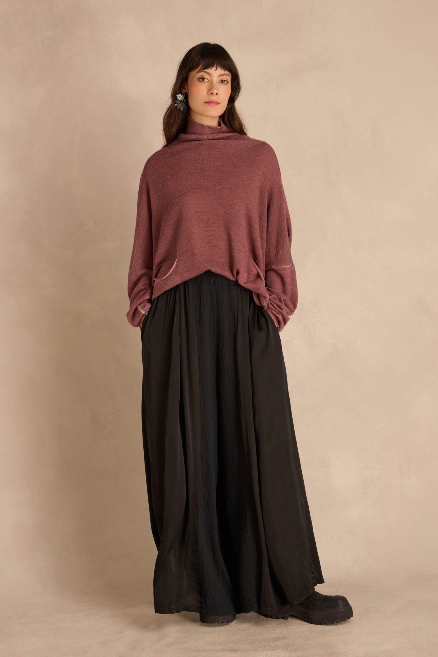 A person wearing a dusty rose cowl-neck sweater and Black Wide Leg Panel Trousers.