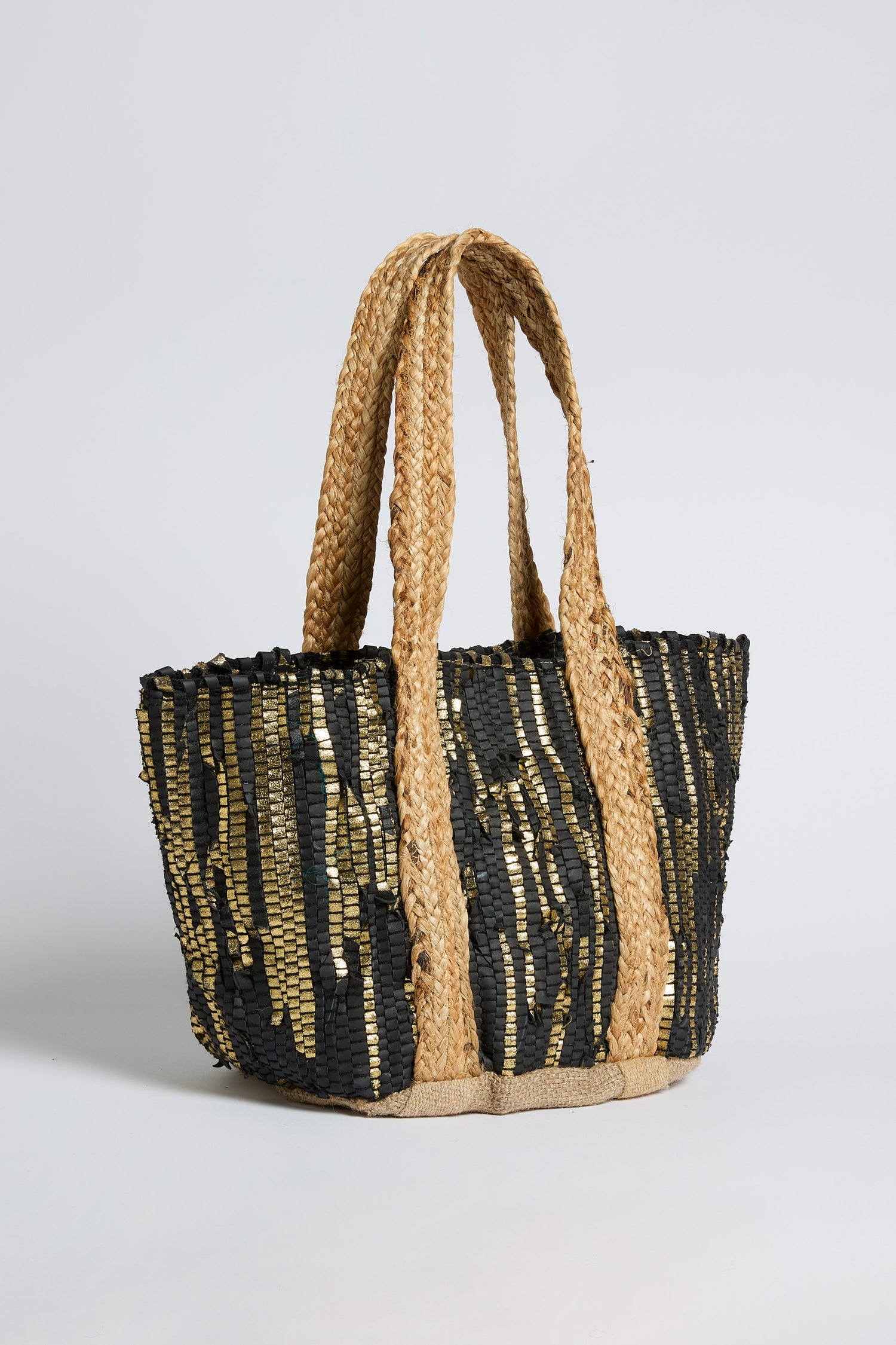 The Black and Gold Upcycled Leather Tote Bag features wide, braided handles and a striking black and gold sequin striped pattern, showcasing sustainable craftsmanship with a handwoven design.
