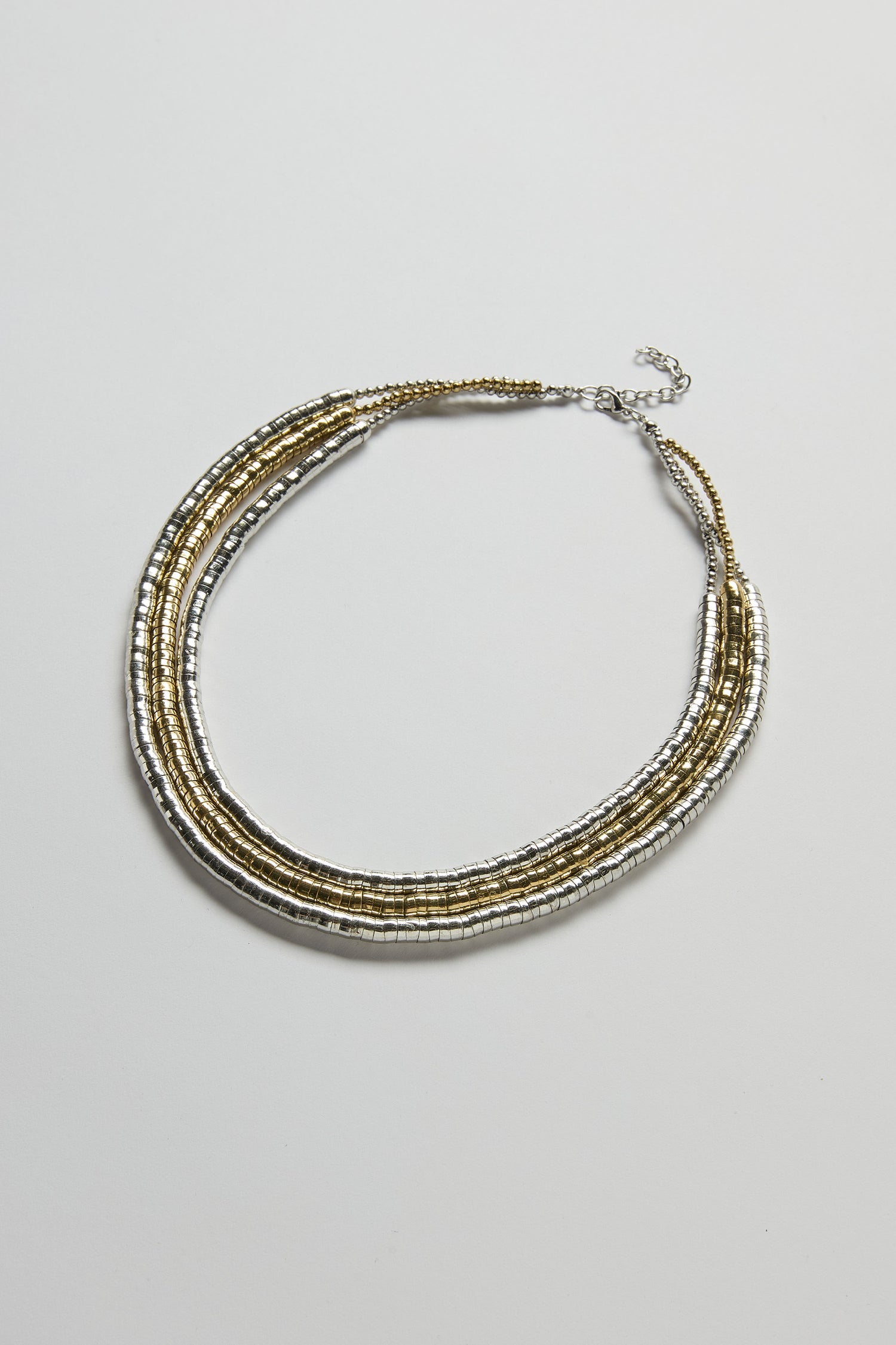 The Triple Strand Disc Necklace features small metallic gold and silver beads with metallic-toned discs on three strands and an adjustable clasp, displayed against a plain white background.