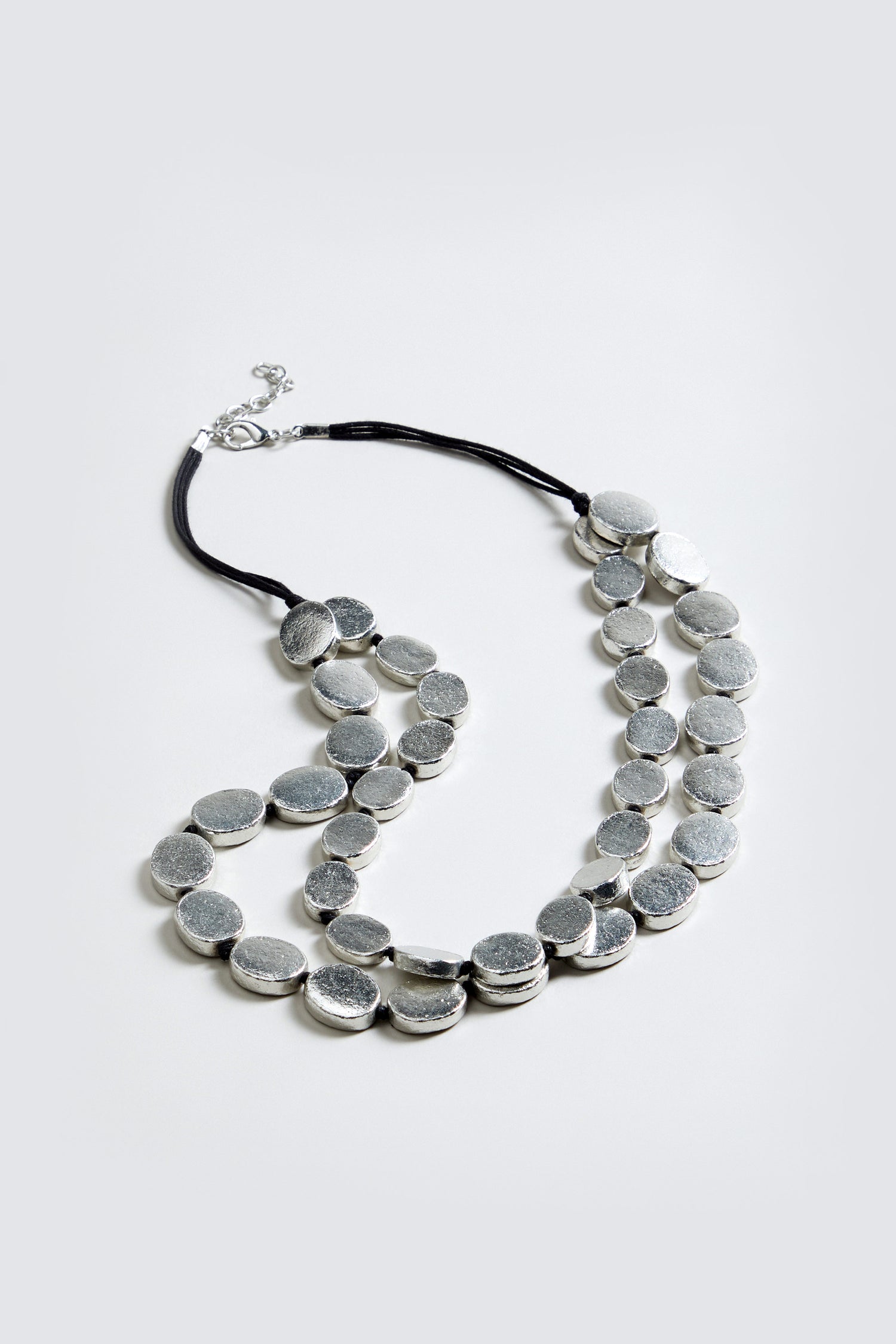 Double Strand Oval Disc Necklace with large, textured silver-toned oval discs on a black cord, shown against a plain light gray background.