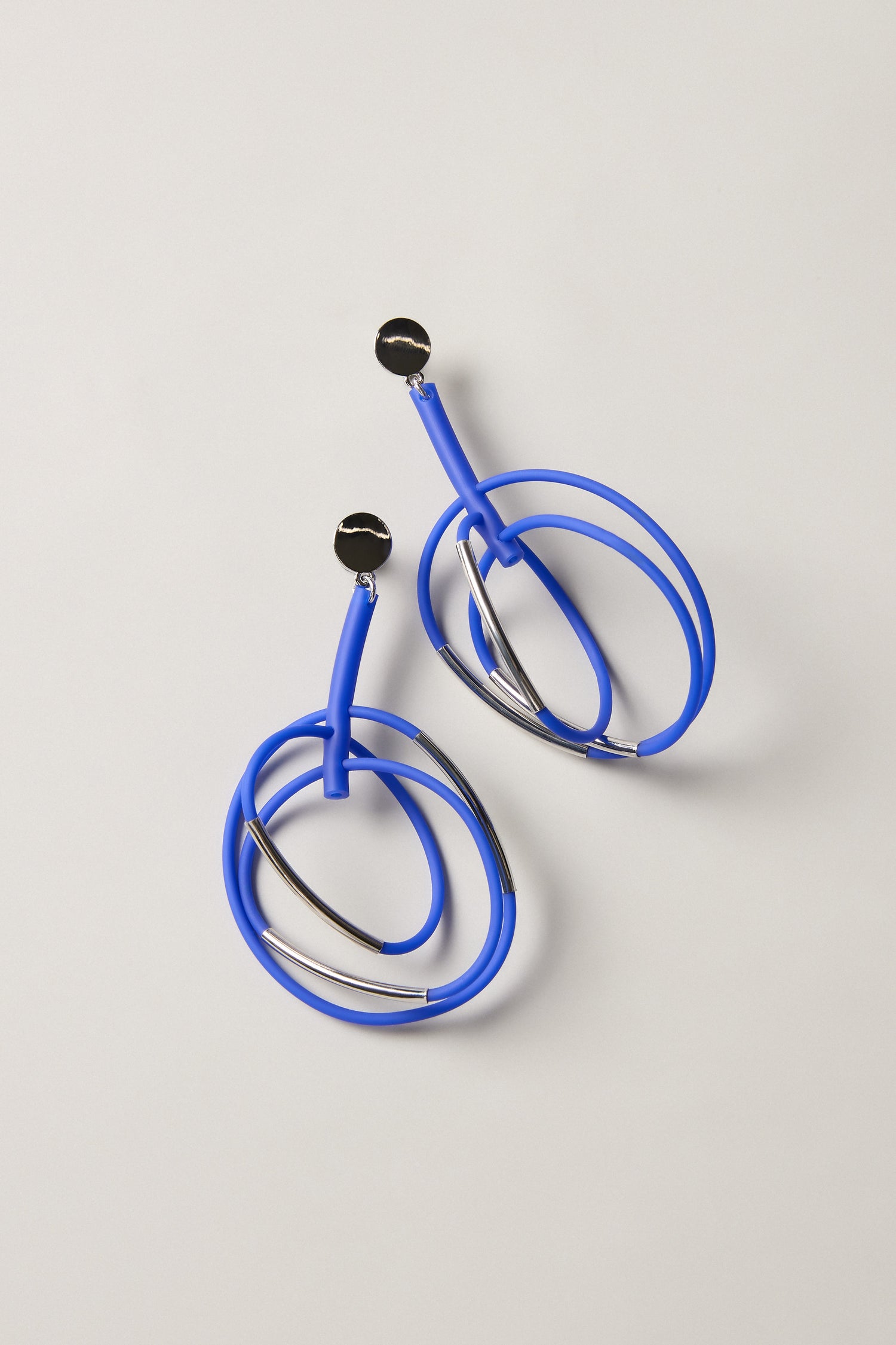 The Carousel Earrings feature blue, silver, and black circular studs, shown on a neutral background—an ideal choice for fans of statement jewellery and modern style.