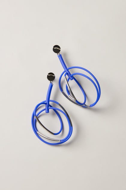 The Carousel Earrings feature blue, silver, and black circular studs, shown on a neutral background—an ideal choice for fans of statement jewellery and modern style.