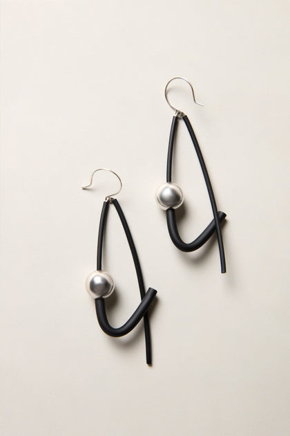 Silver Sphere Earrings: Abstract black drop earrings featuring curved lines and silver sphere accents, displayed on a light neutral background—an eye-catching example of modern jewellery design.
