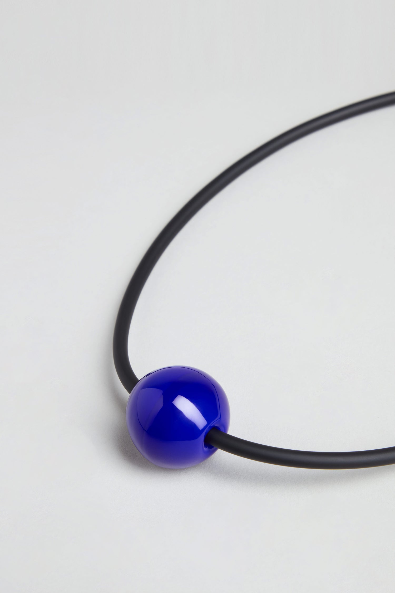 The Murano Bead Necklace is a minimalist piece featuring one large, glossy blue Murano bead. Handmade in Paris, it is shown on a plain white background.