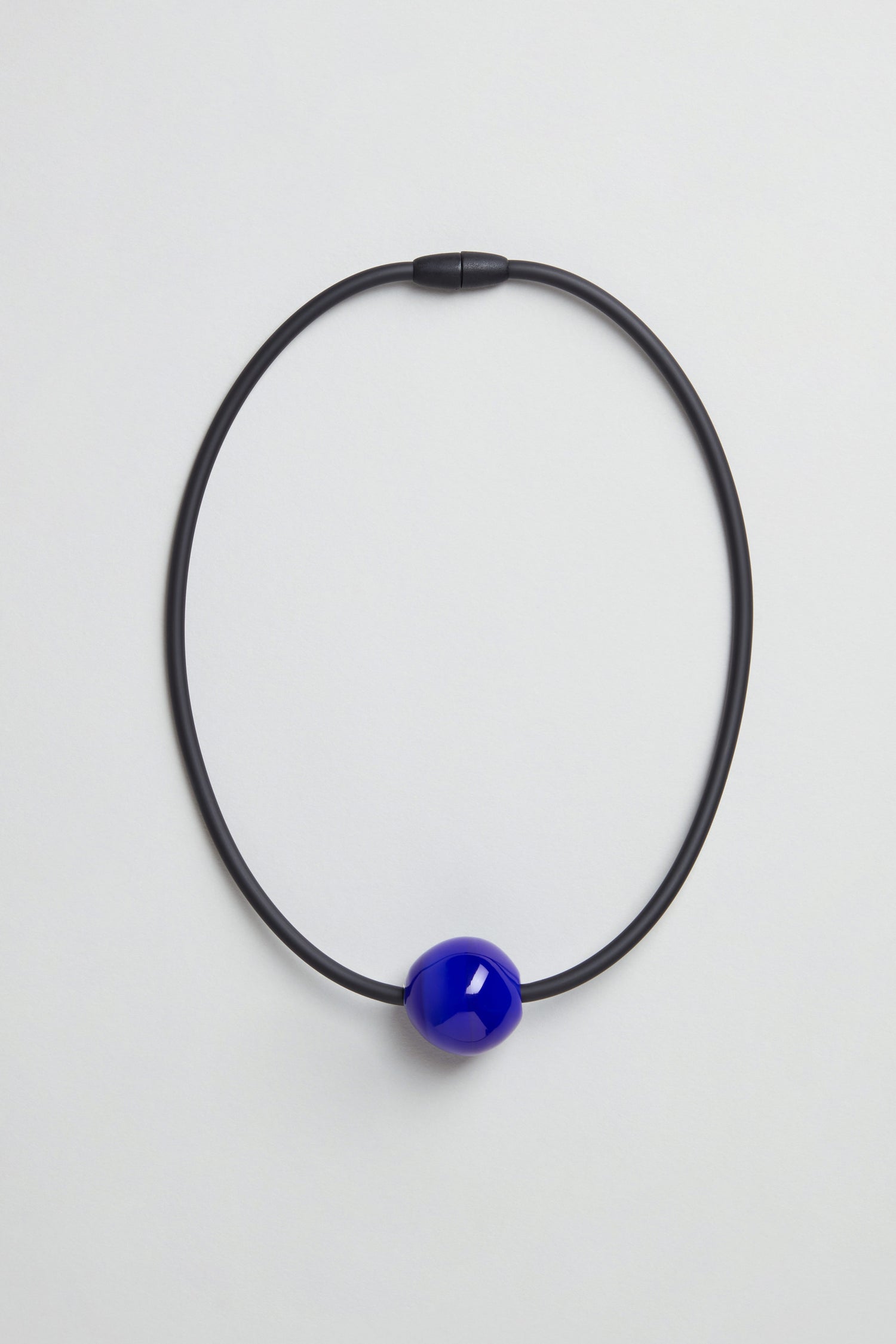 The Murano Bead Necklace is a minimalist, handmade piece from Paris with a single glossy blue bead on a black cord, shown against a plain light background.