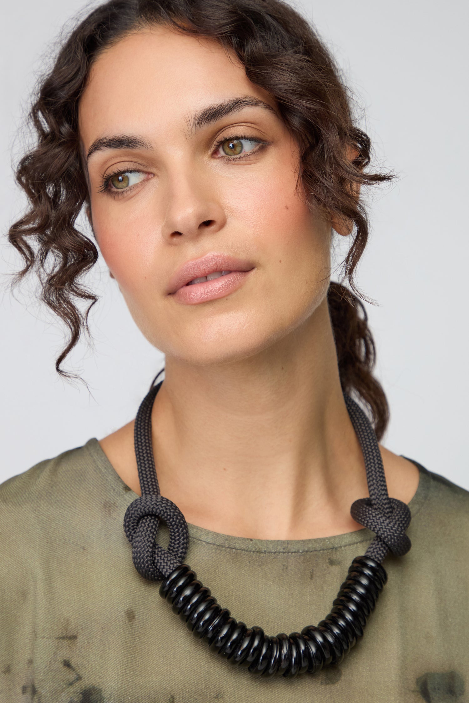 Woman with wavy brown hair wears a greenish top and the Murano Glass Rings Necklace with chunky glass rings, set against a neutral background.