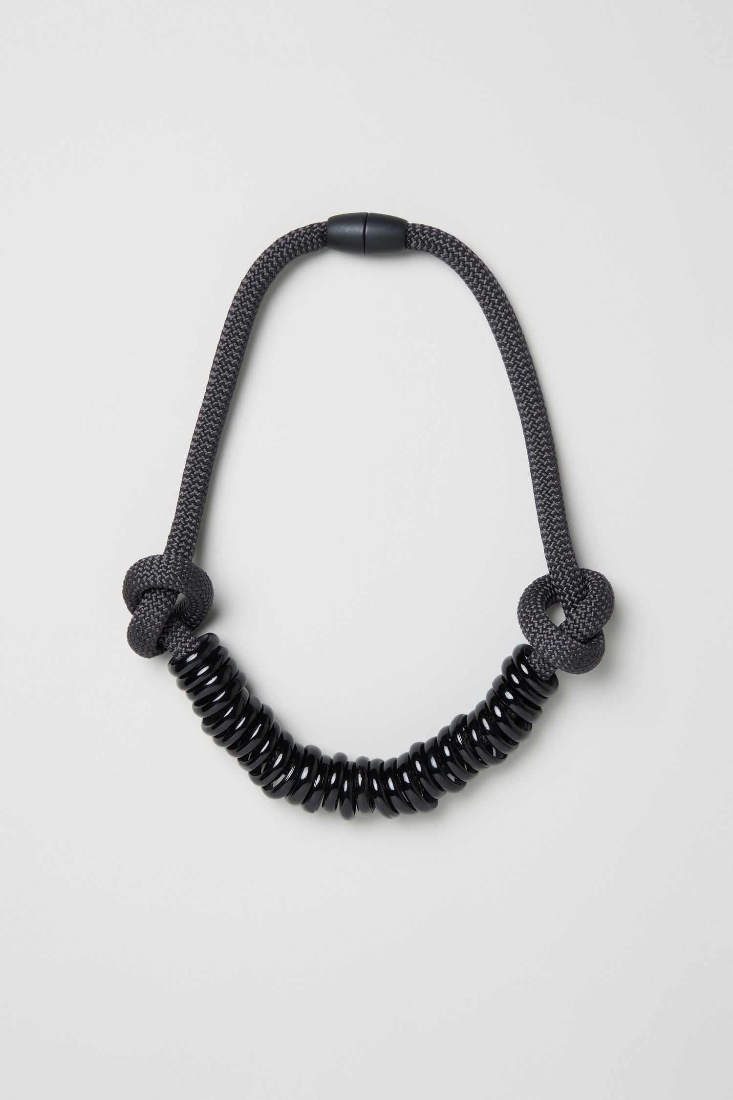 The Murano Glass Rings Necklace features a black cord with two knot details and black circular beads strung at the center, shown on a plain light background.