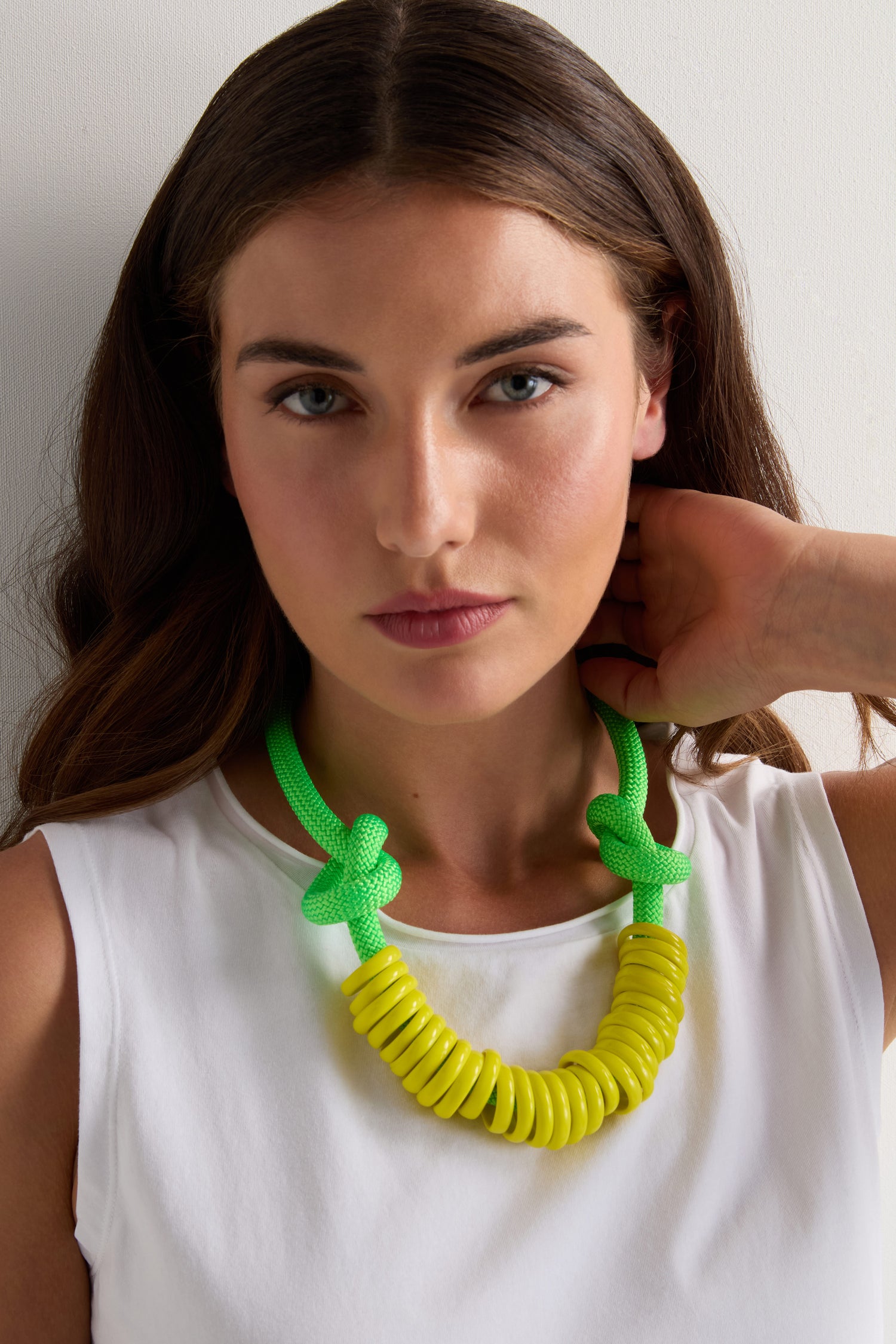 A woman in a white sleeveless top stands against a plain light background, showcasing the Murano Glass Rings Necklace in neon green and yellow.