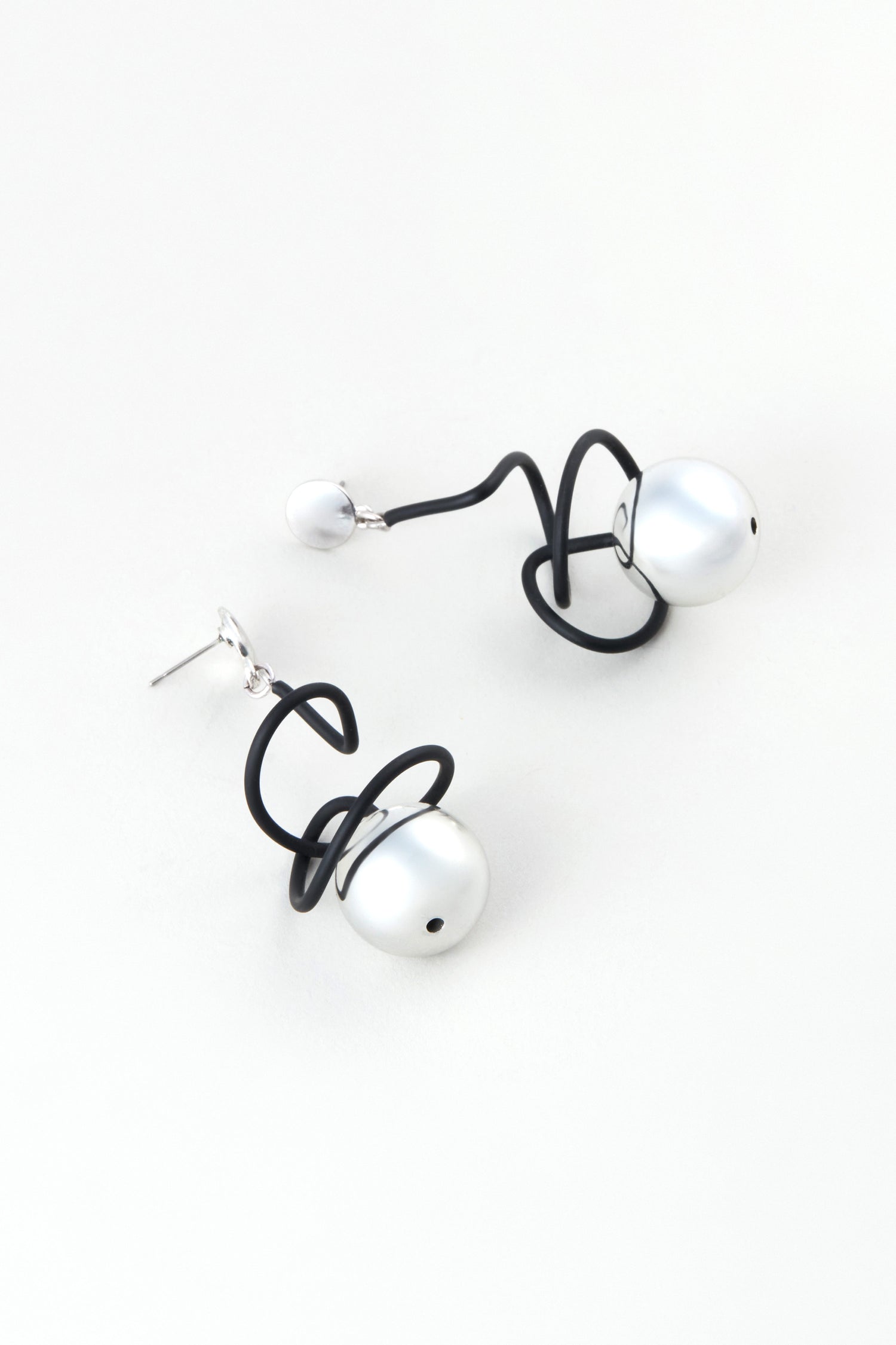 The Graphic Squiggle Earrings by Samuel Coraux showcase large white pearls and black abstract wire loops, presented on a plain white background.