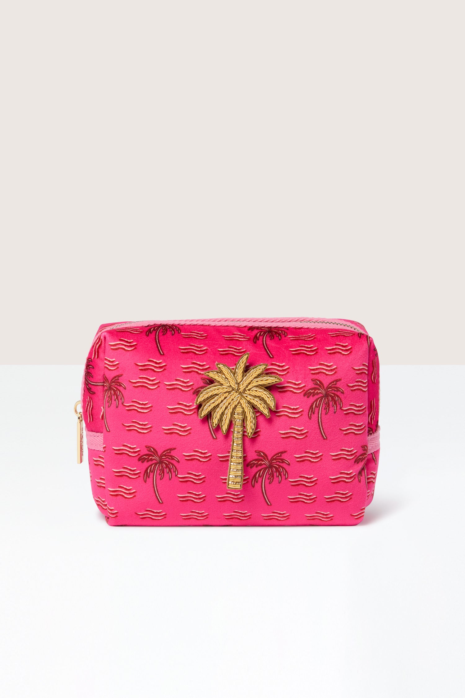 The Large Palm Make-Up Bag in pink, showcasing a gold palm tree design and zipper closure, adorned with small black and gold palm tree patterns, exudes tropical elegance.