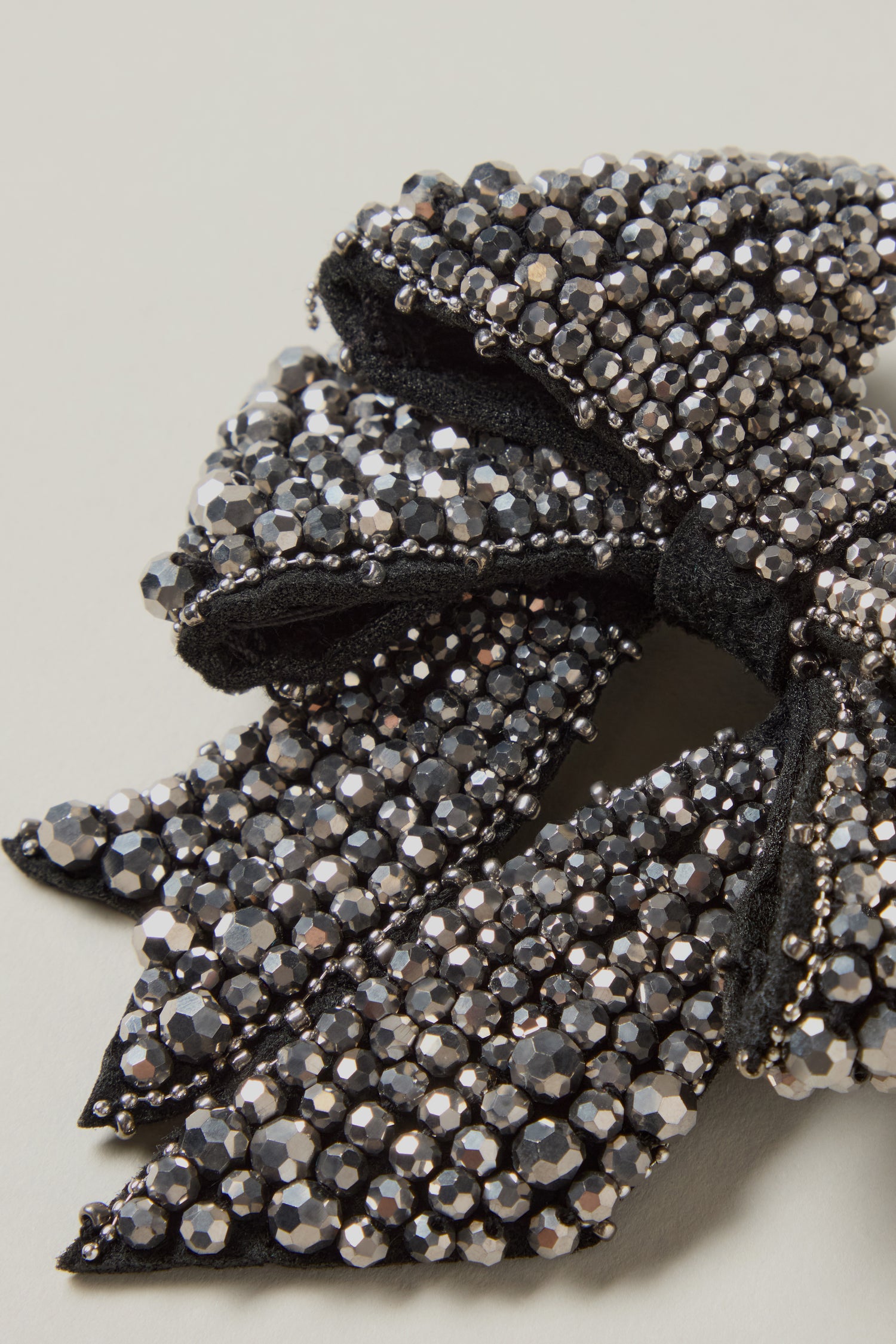 Close-up of the Hand Beaded Bow Brooch, intricately crafted with black beads and embellished with shiny silver and black rhinestones.