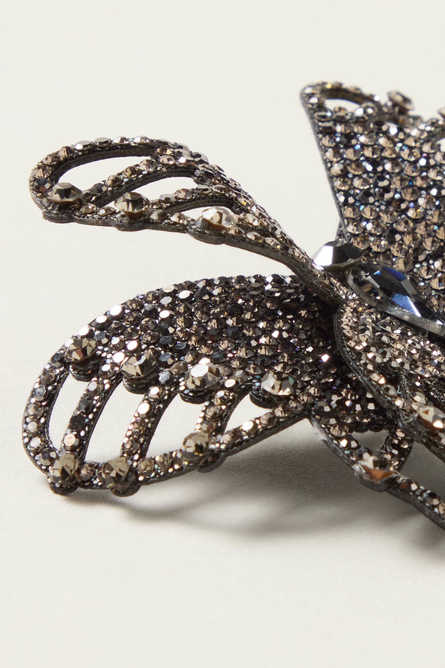 Close-up of the Crystal Butterfly Brooch, a decorative dark crystal accessory encrusted with rhinestones, shown against a plain light background.