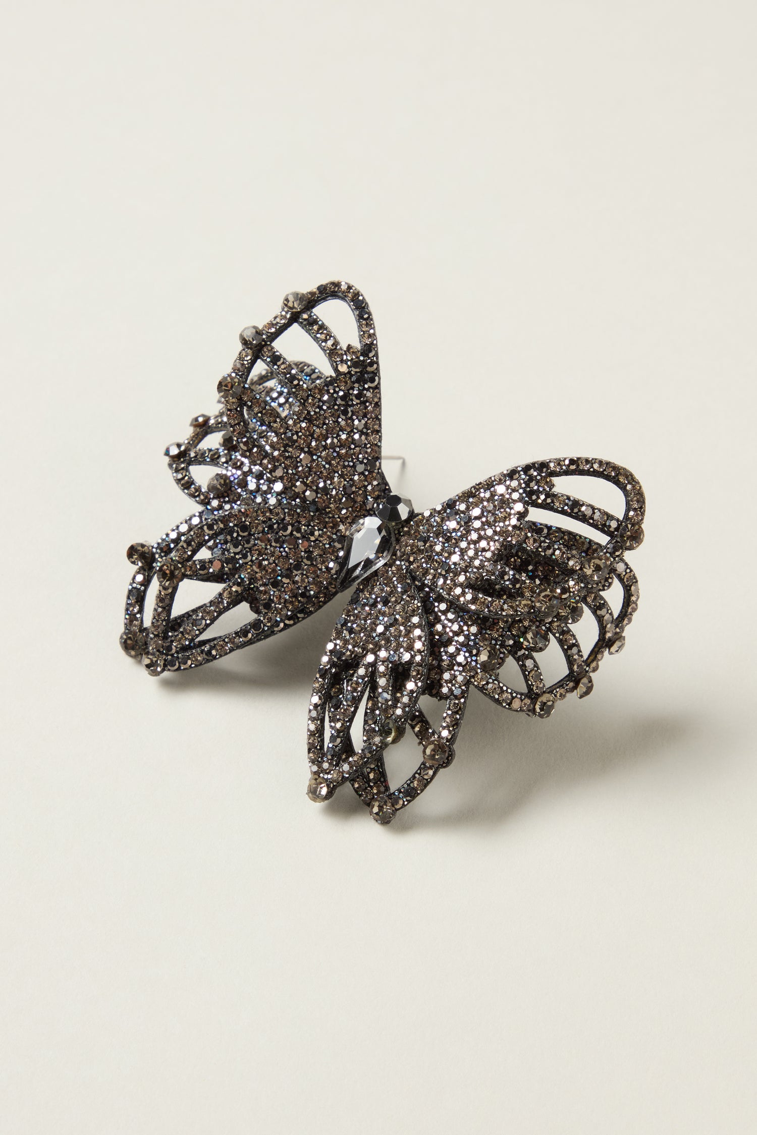 The Crystal Butterfly Brooch, adorned with dark sparkling rhinestones, highlights the elegance of nature-inspired jewelry against a plain light background.
