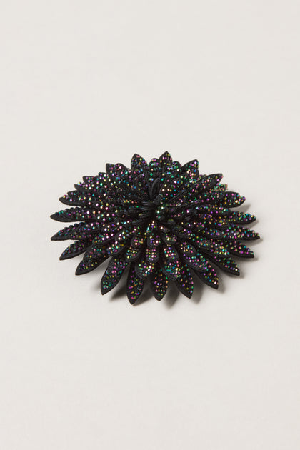 The Dahlia Flower Brooch is a stunning black beaded accessory, inspired by dahlia petals and embellished with multicolored sparkling rhinestones, shown against a plain white background.