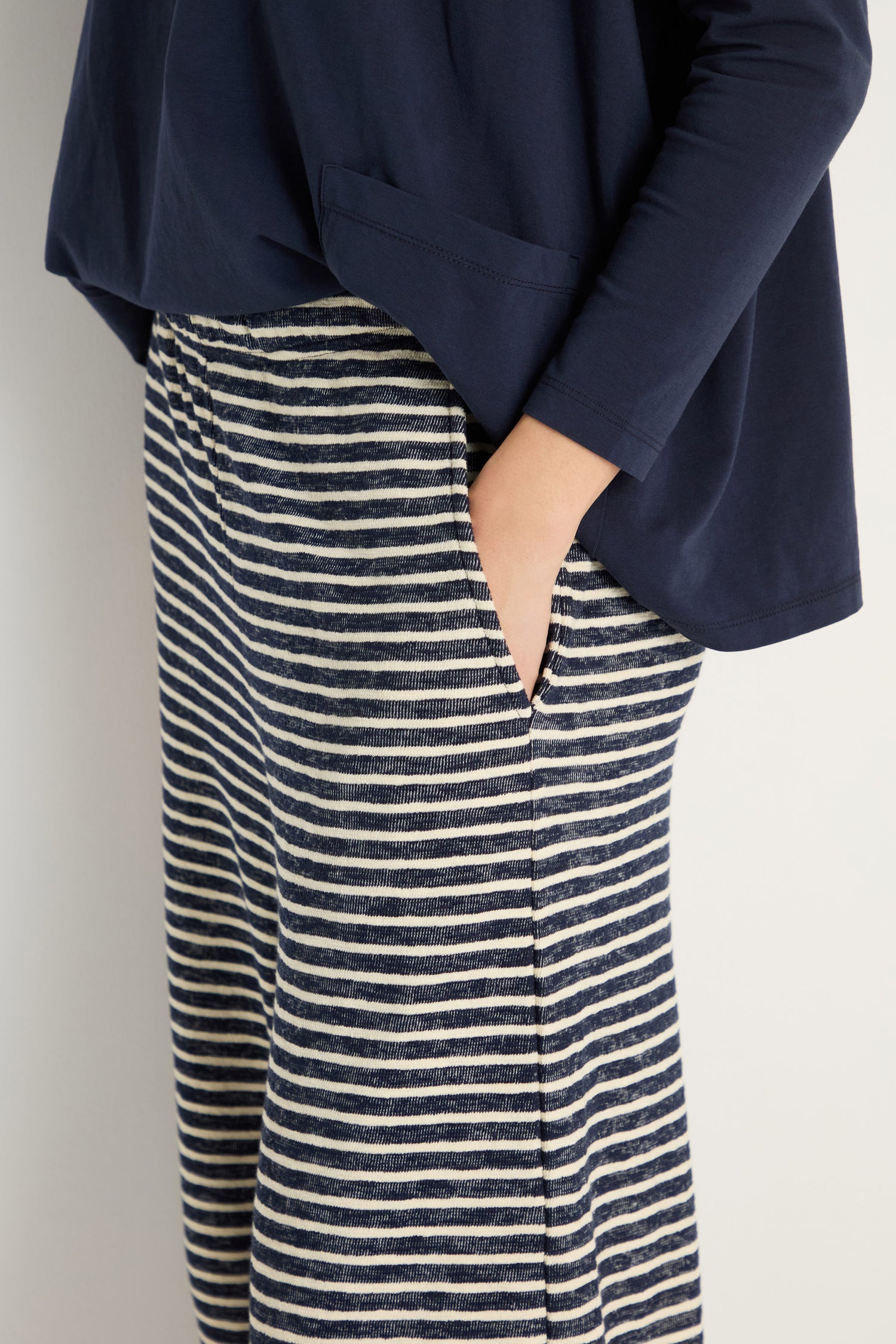 A person wearing a navy long-sleeve top and Textured Stripe Jersey Bubble Trouser stands with one hand in their pocket.