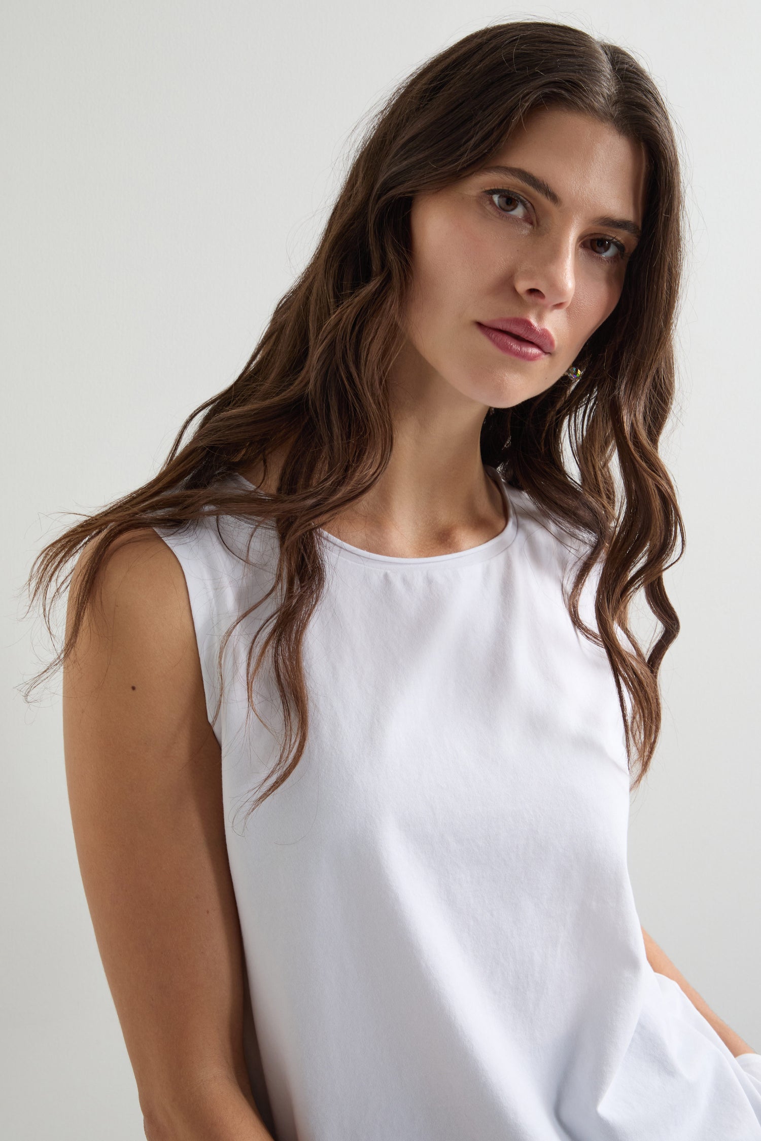 A woman with long brown hair is wearing a white Cotton Jersey Boxy Vest, looking at the camera with a neutral expression.