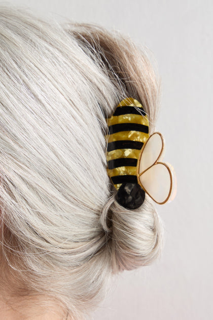 Close-up of silver hair styled in a twist, secured with the Hand-Painted Bee Hair Clip featuring yellow, black, and white details.